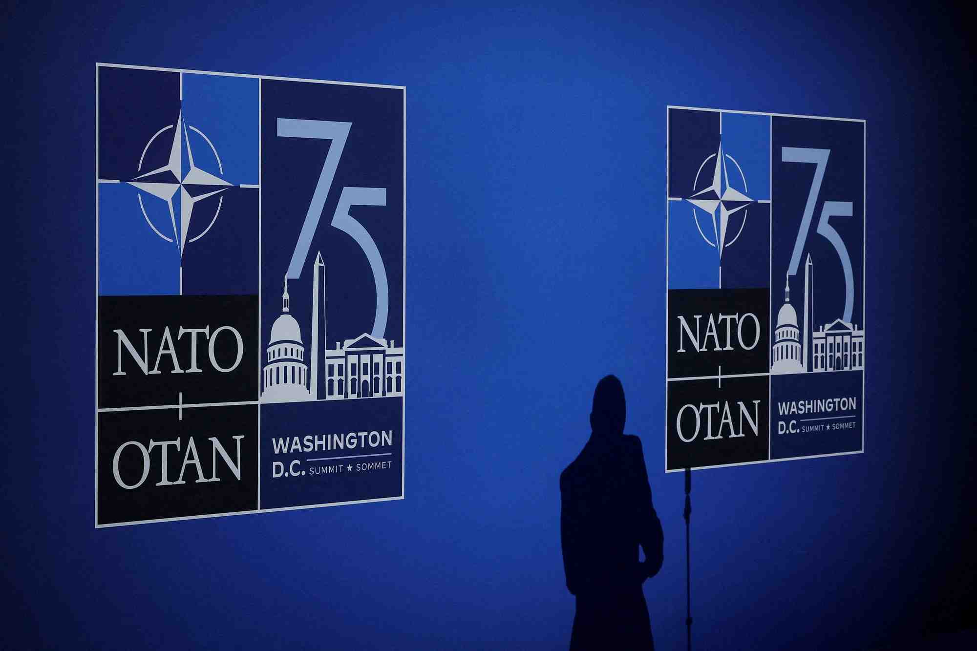 L'ombre d'un journaliste se dessine a cote des logos lors de l'evenement de celebration du 75eme anniversaire de l'otan a washington