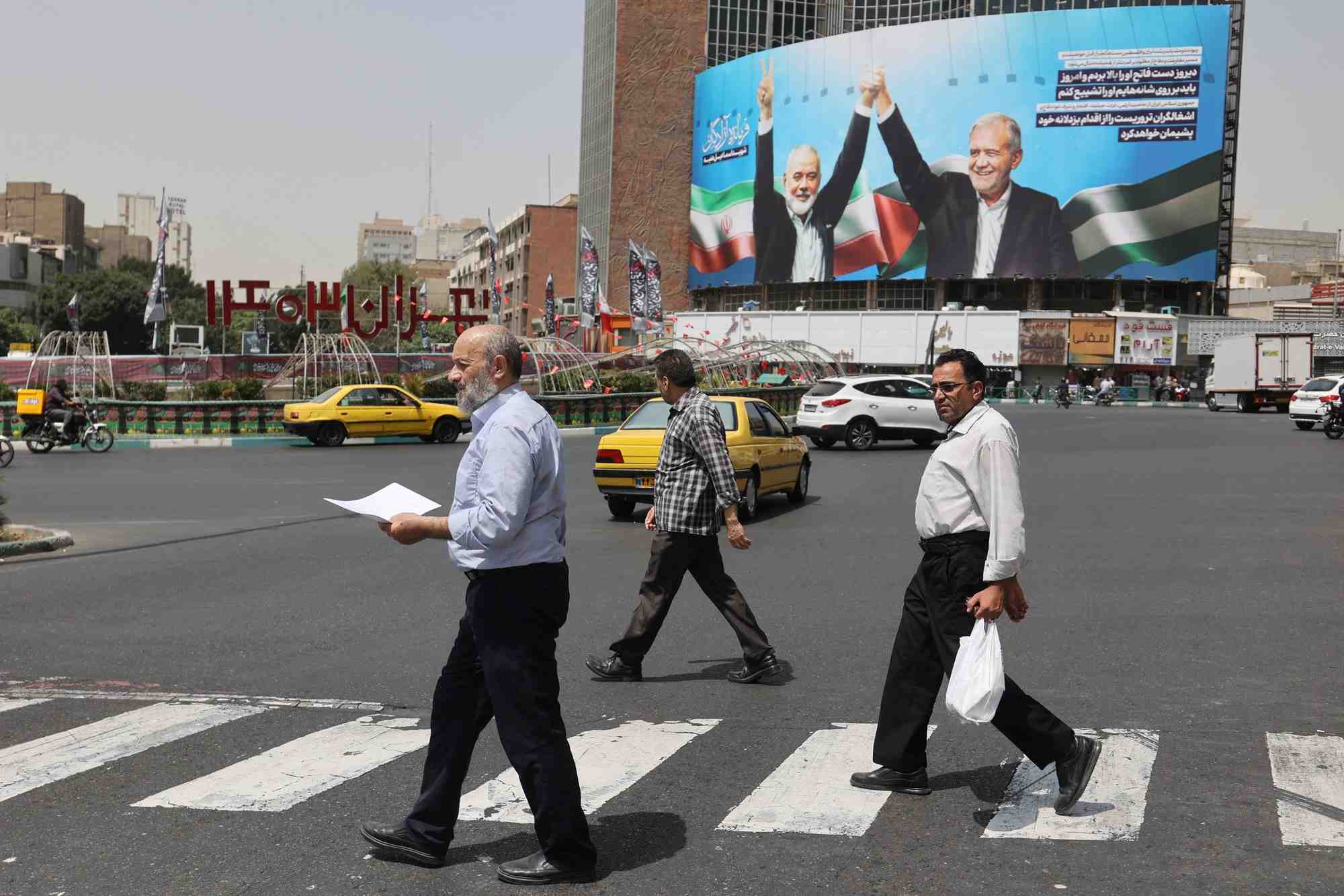 Des passants devant une photo du chef du hamas assassine, ismail haniyeh, et du president iranien, masoud pezeshkian, a teheran, en iran