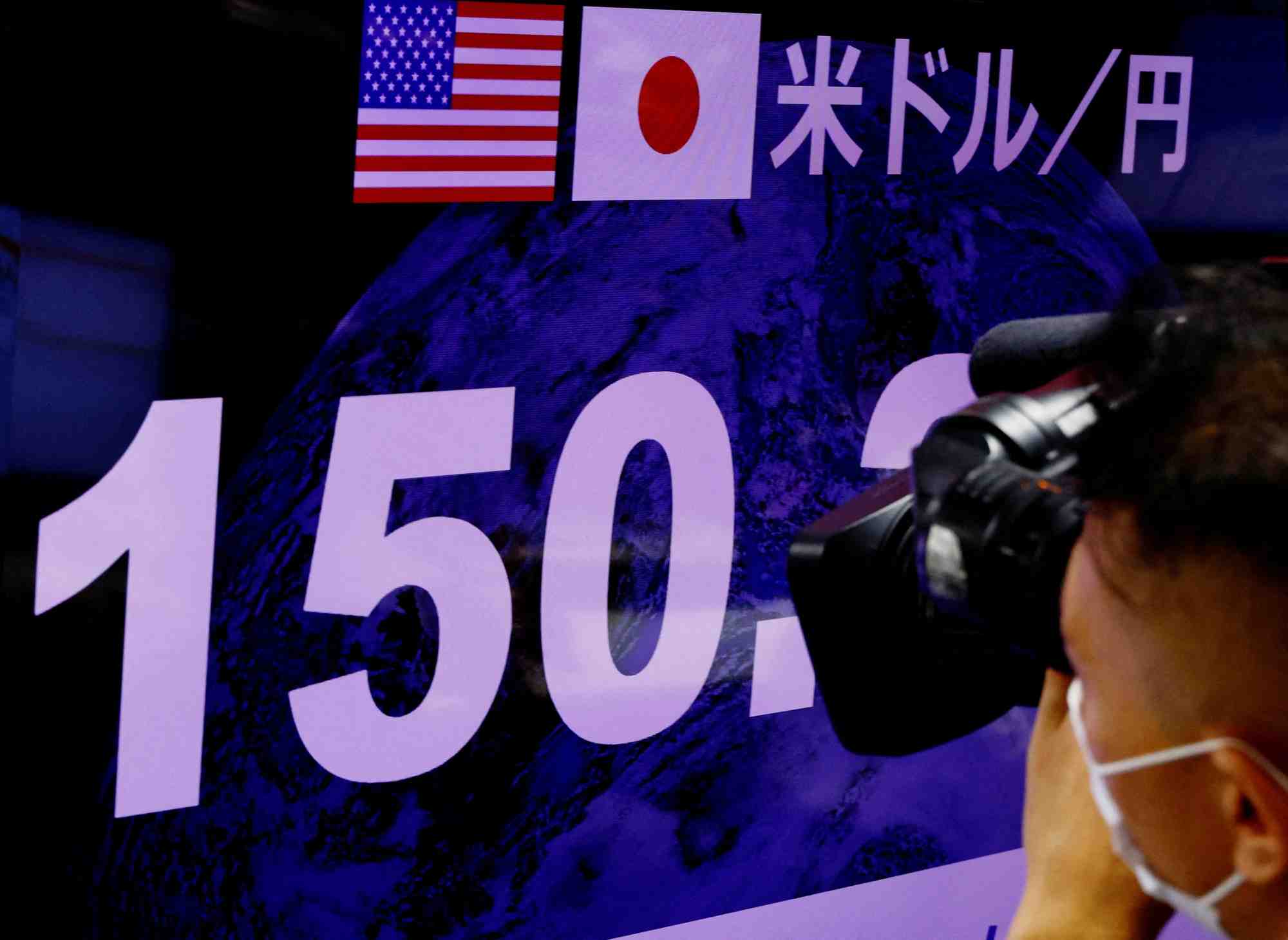 Un cameraman de television filme le taux de change du yen japonais par rapport au dollar americain a tokyo, au japon