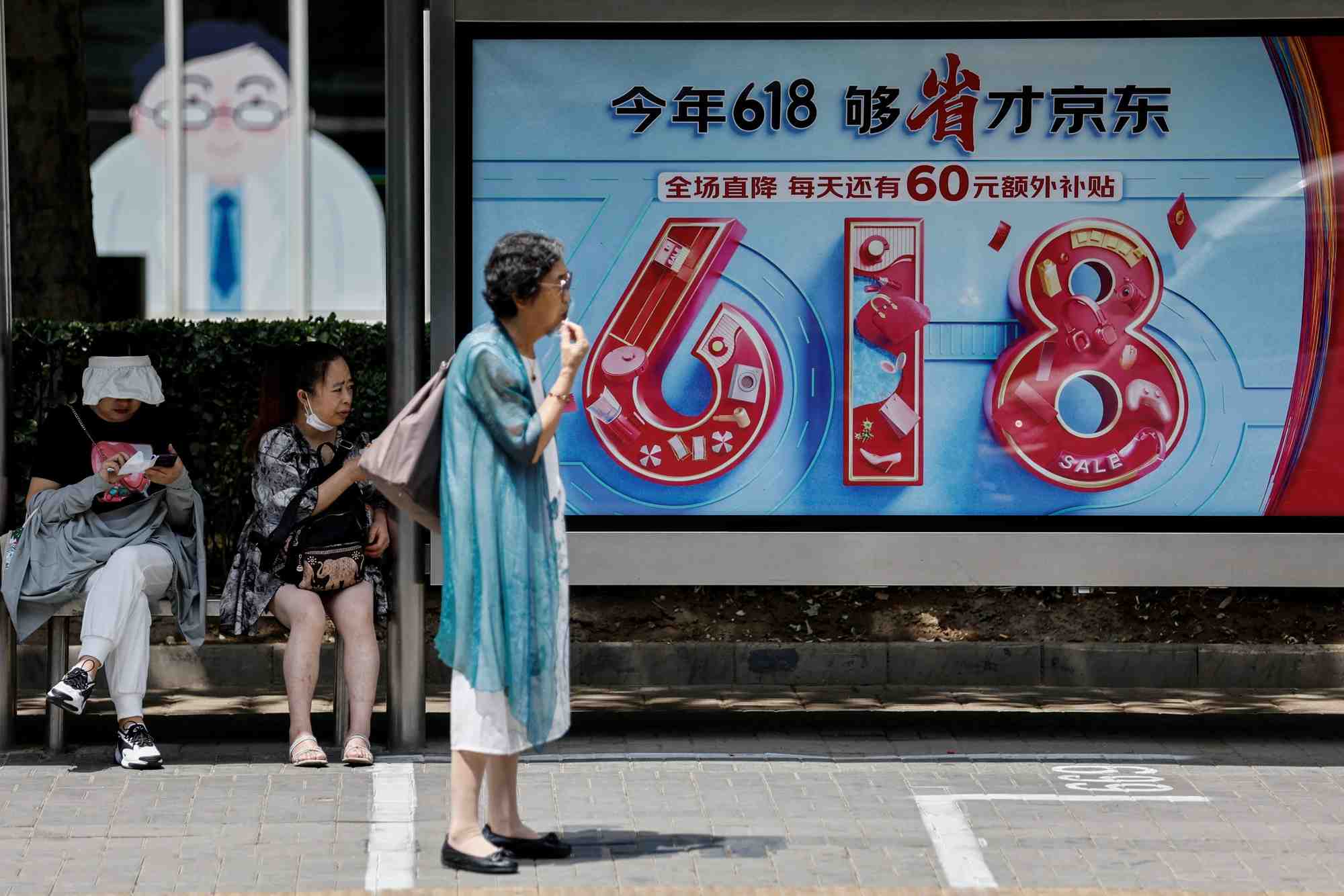 Des personnes attendent le bus pres d'un panneau publicitaire de jd.com pour le festival du shopping "618", a pekin