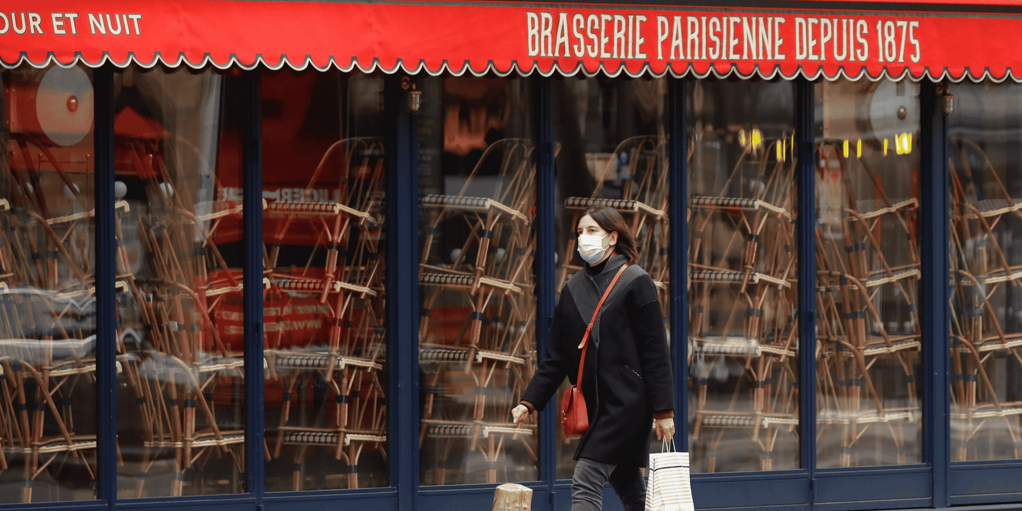 France / coronavirus / confinement : une femme portant un masque passe devant un restaurant fermé à Paris le 25 novembre 2020