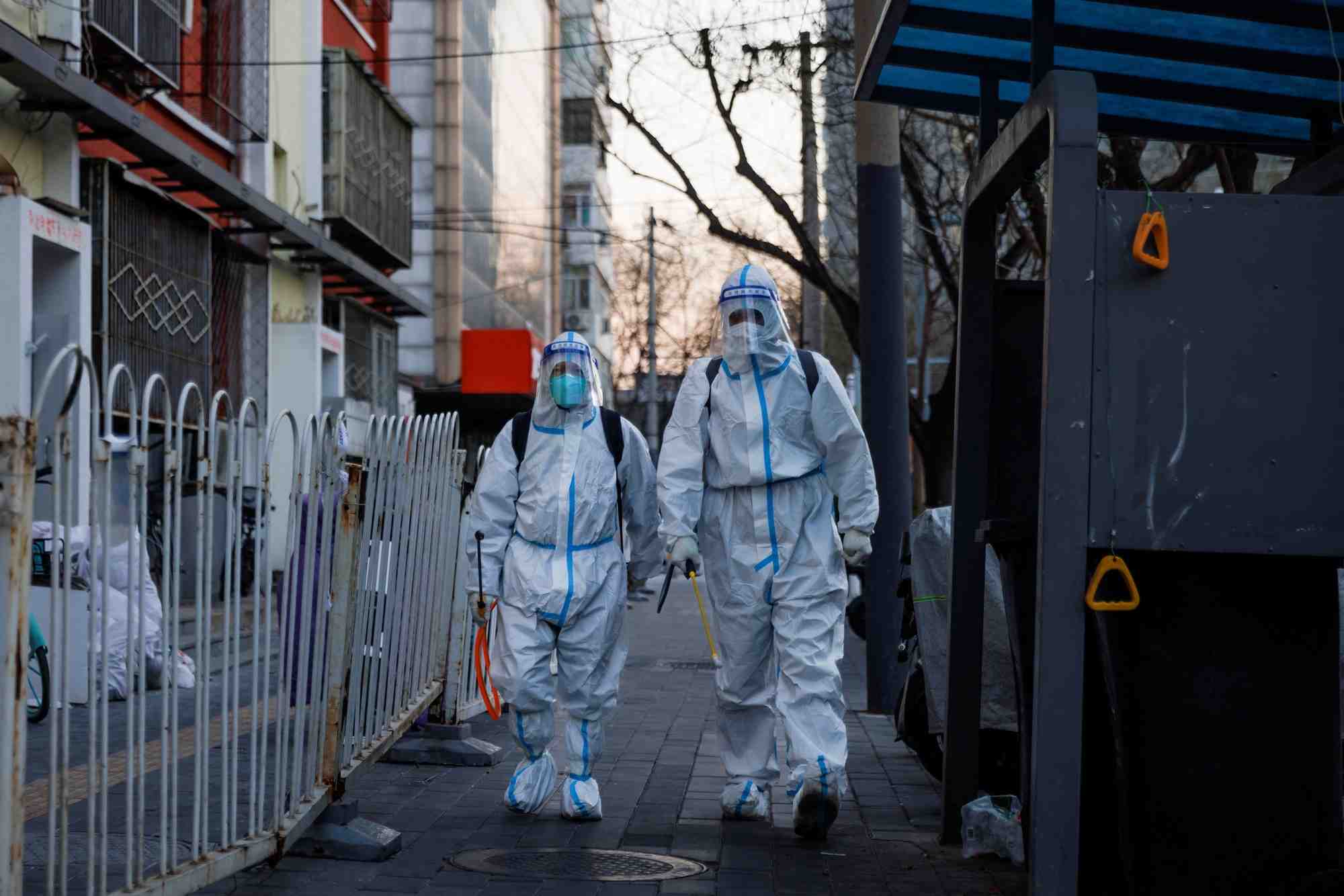 Photo des agents de prevention, dedies a la lutte a la pandemie de la covid-19, marchent dans une rue de pekin