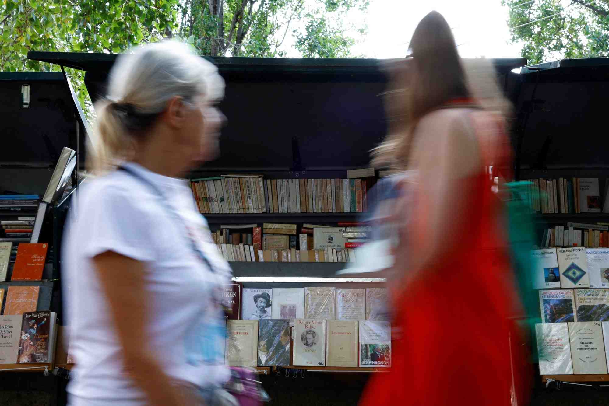 Des personnes passent devant des bouquinistes sur les quais de la seine a paris