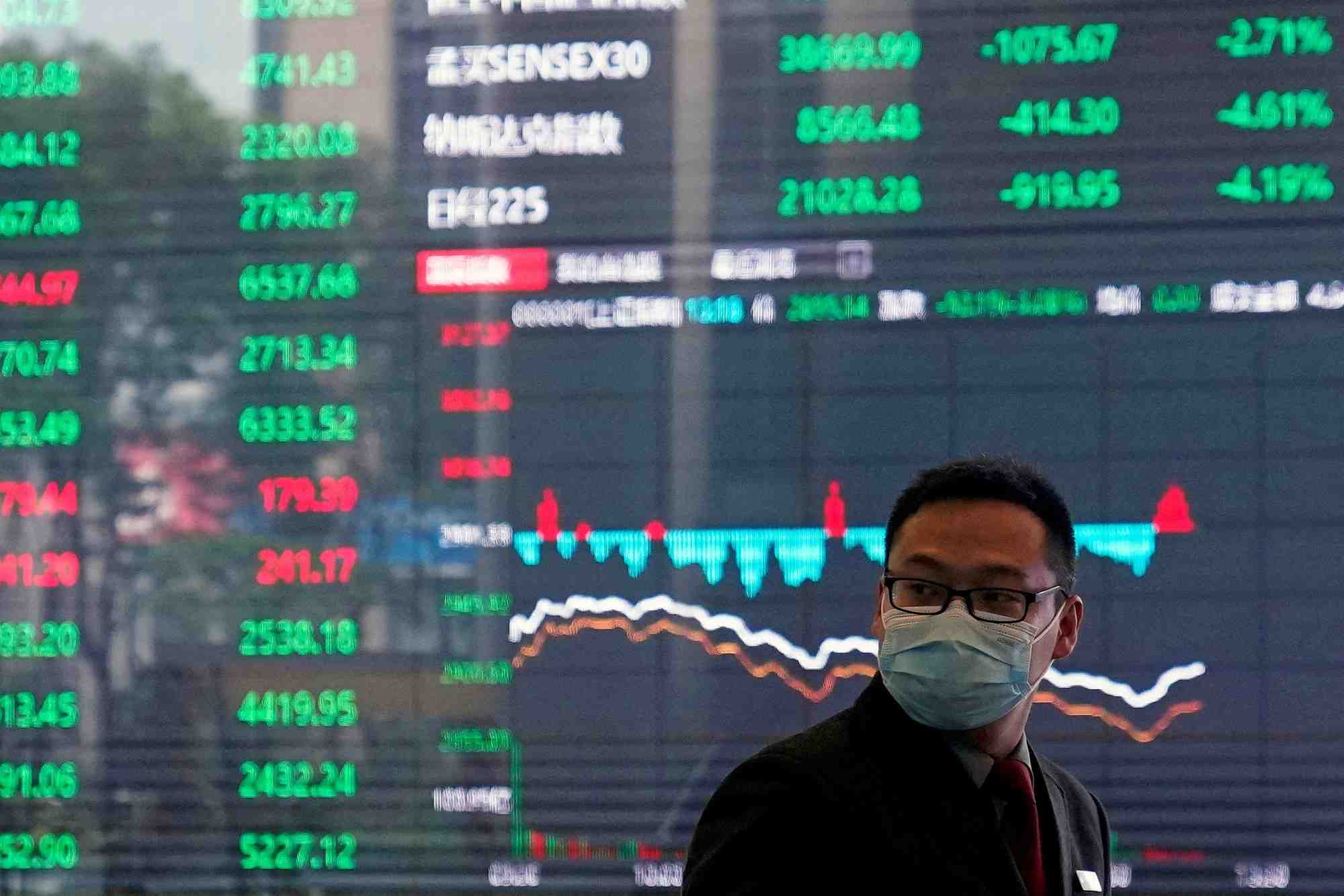 Un homme portant un masque de protection est vu a l'interieur du batiment de la bourse de shanghai