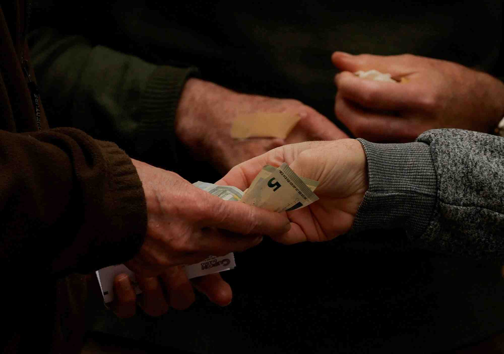 Un client paie un vendeur de loterie de rue avec des billets de cinq euros