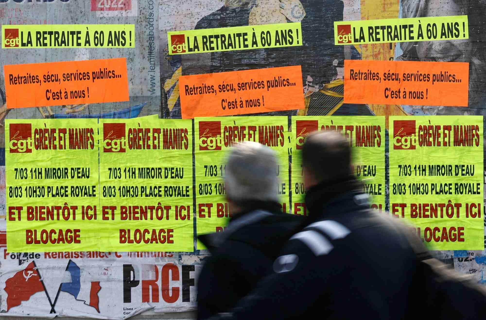 Des gens passent devant des affiches a bouguenais appelant a la greve et a des manifestations contre le plan de reforme des retraites du gouvernement