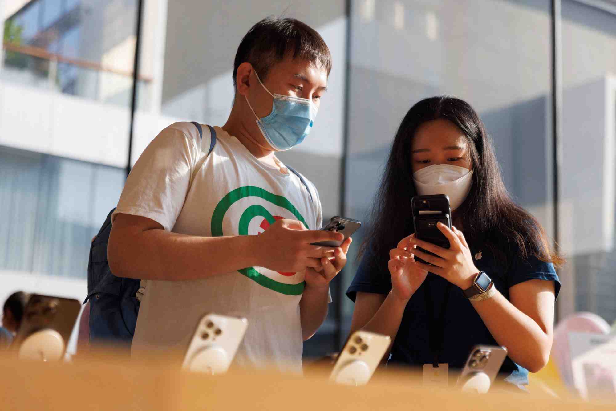 Un client et une vendeuse regardant un iphone dans un apple store a pekin