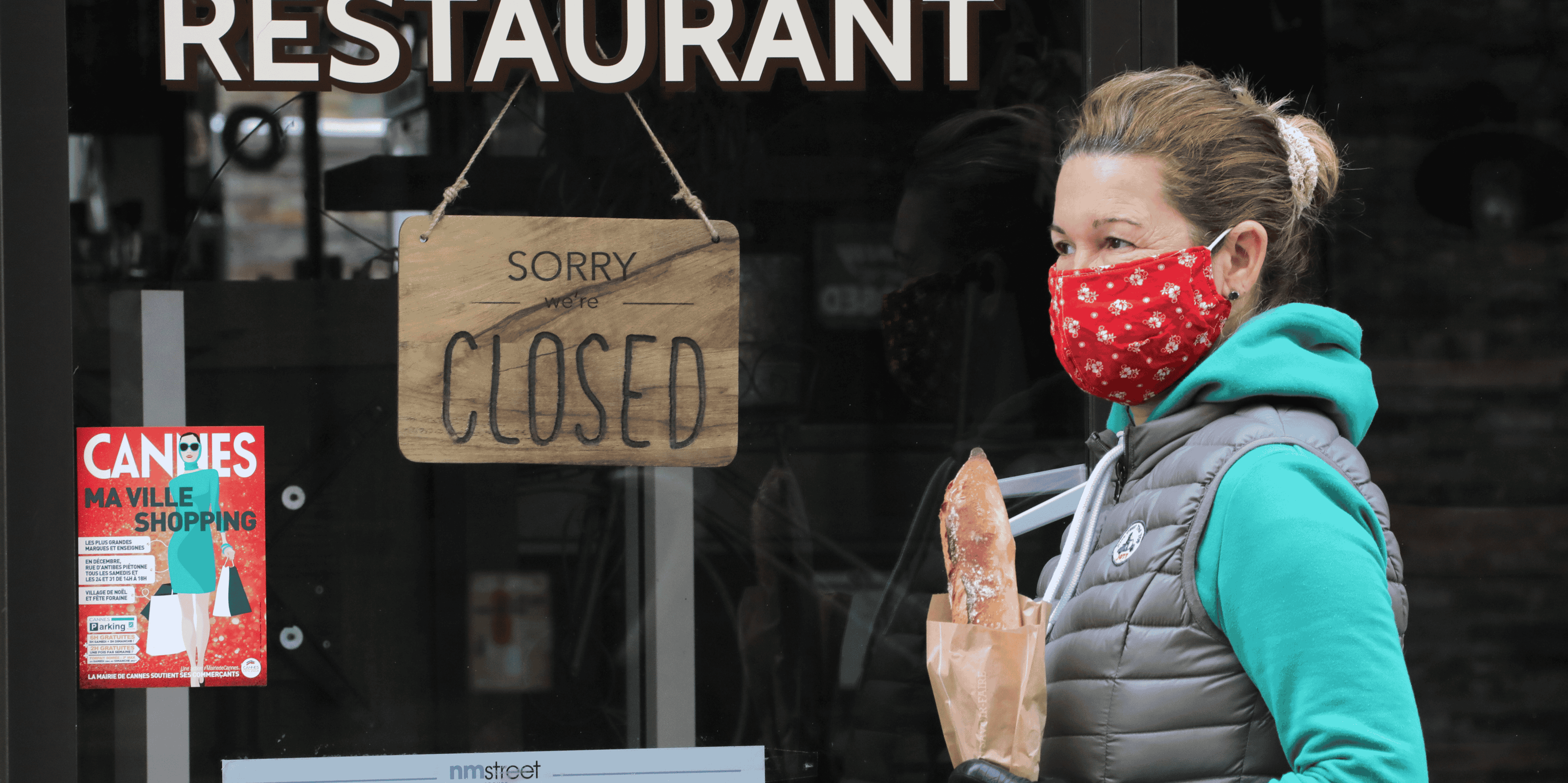 Fermeture commerce restaurant. Une femme portant un masque et une baguette passe devant un restaurant fermé à cause de l'épidémie de coronavirus, le 16 avril 2020 à Cannes