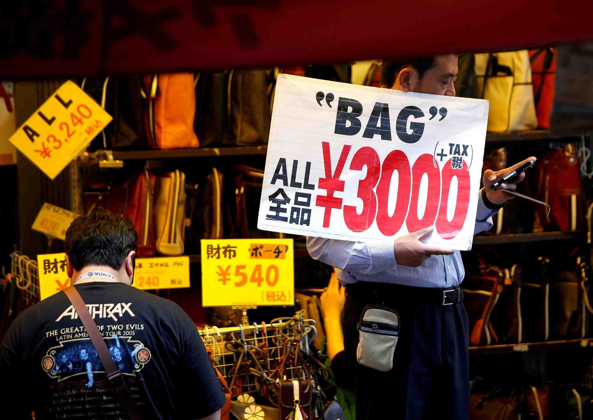 Un employe de magasin tient une pancarte pour attirer les clients a tokyo