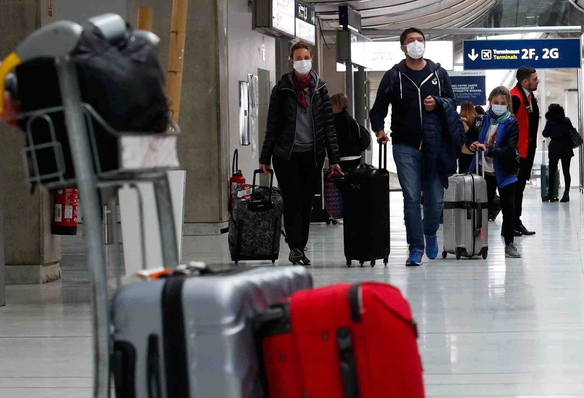 Des personnes portant des masques de protection arrivent a l'aeroport charles de gaulle pres de paris