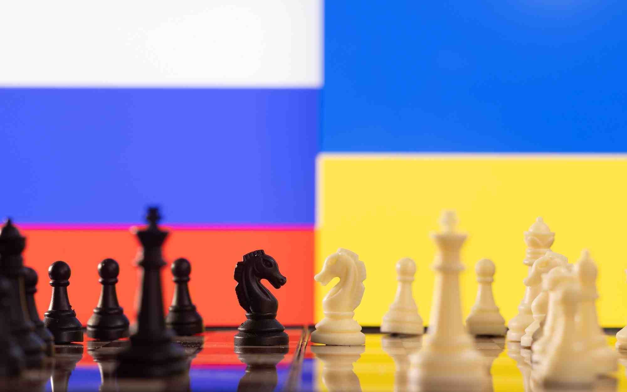 Des pieces de jeu d'echec devant les drapeaux de la russie et de l'ukraine