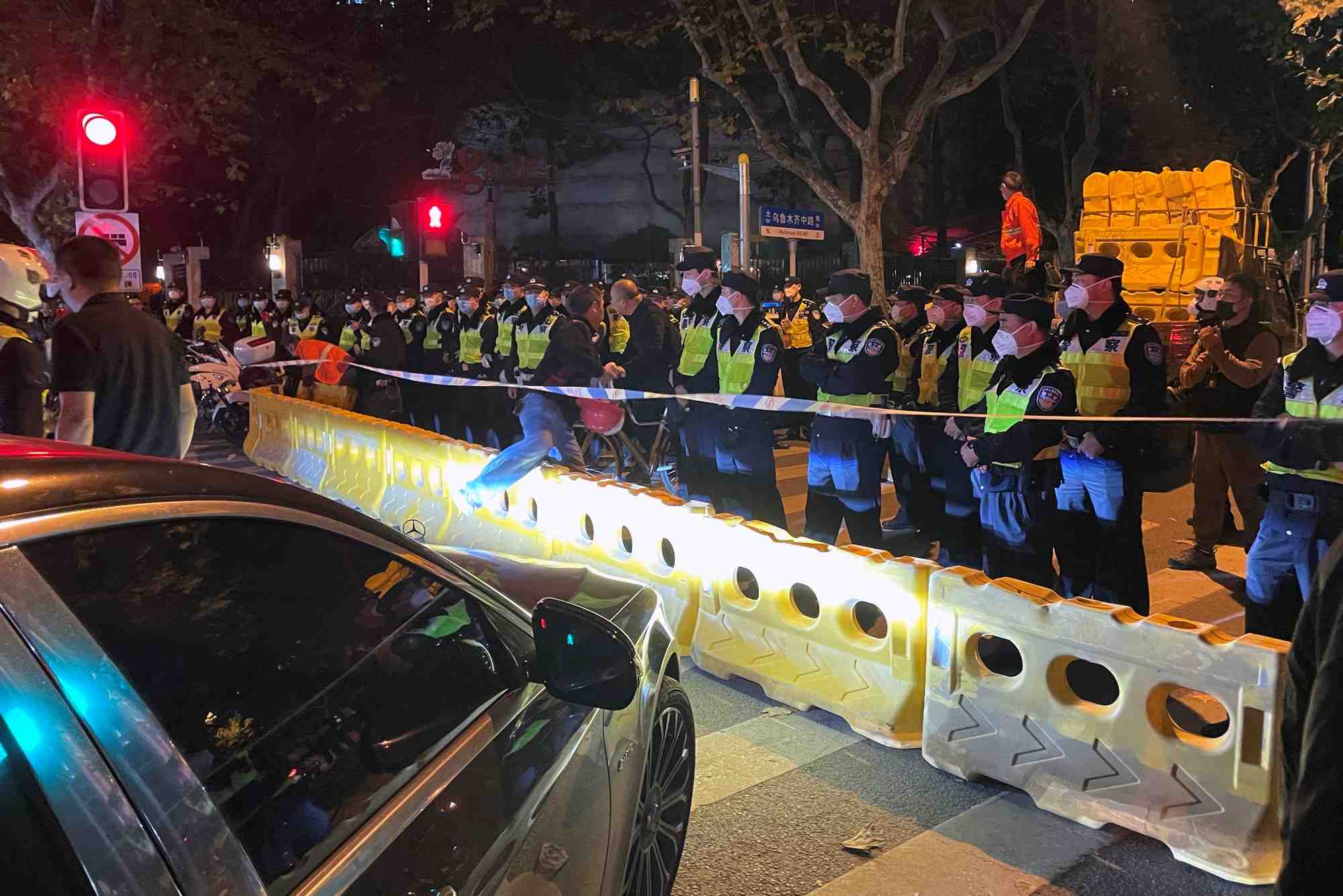 Des policiers derriere des barricades sur le site ou une manifestation contre les restrictions liees au covid-19 a eu lieu la nuit precedente, a shanghai, en chine