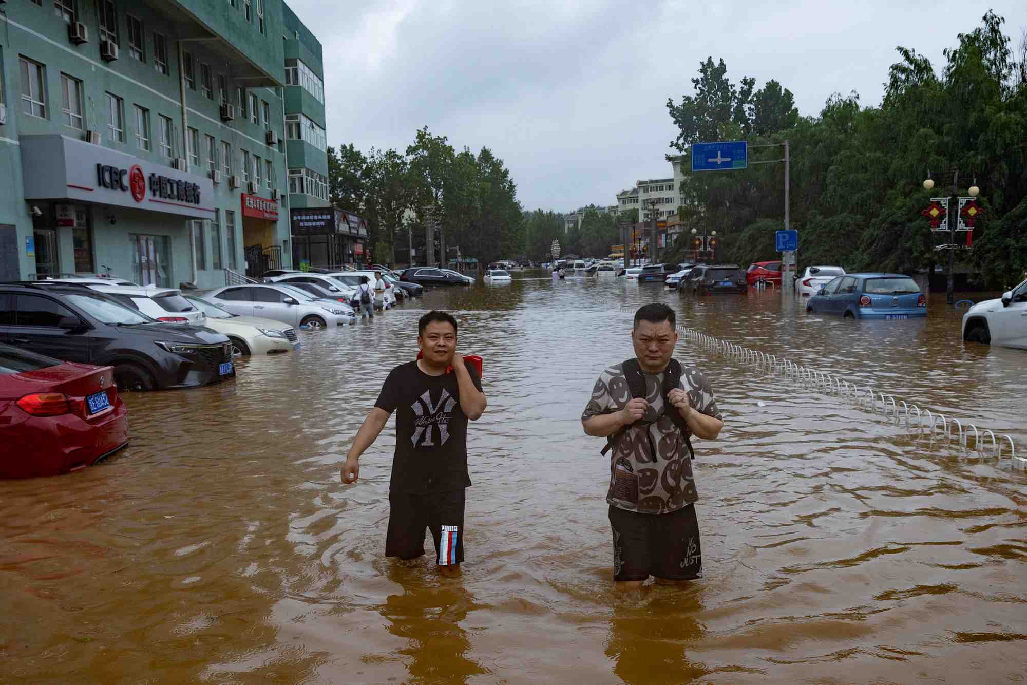 Des gens marchent dans une rue inondee a pekin