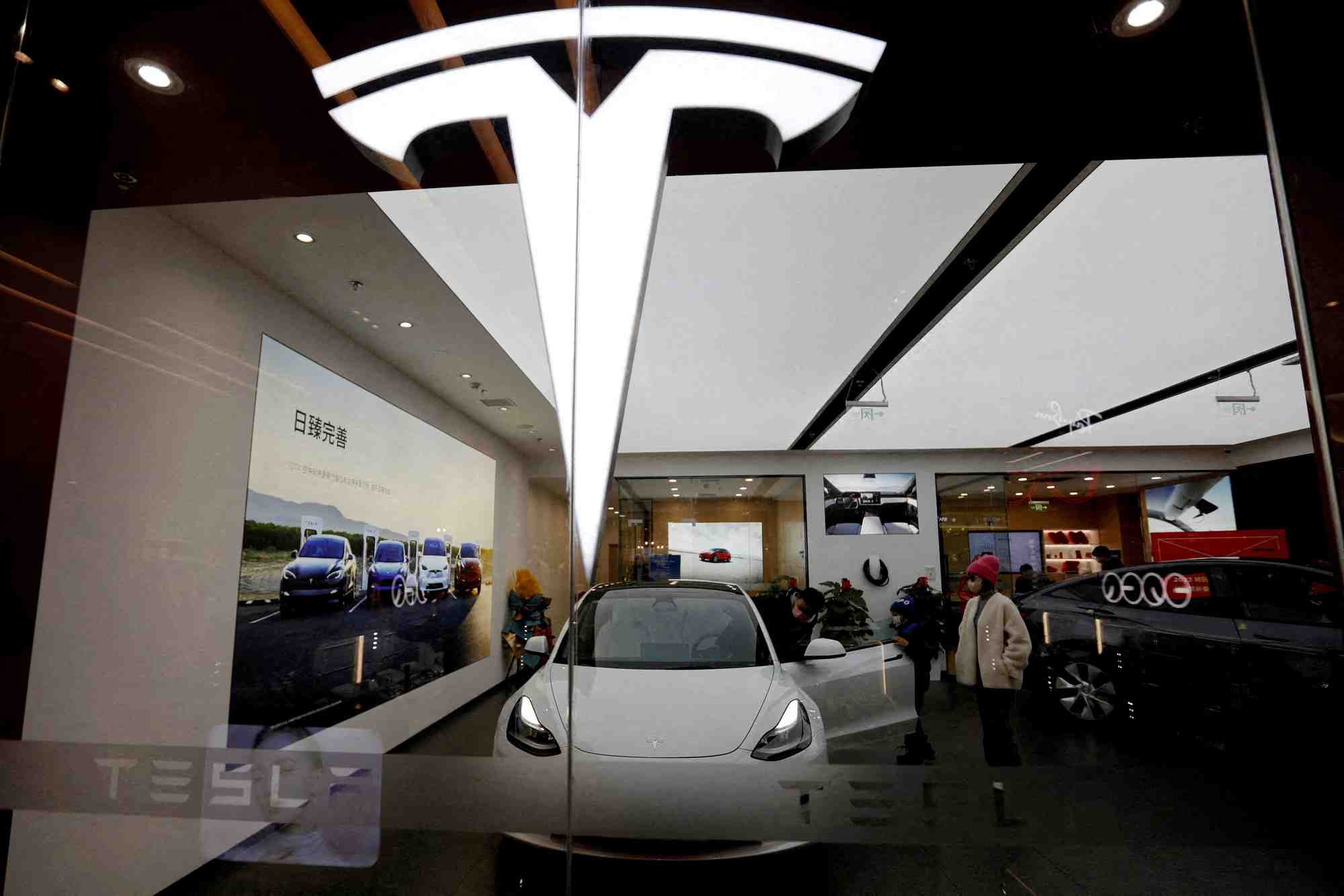 Des visiteurs observent une voiture tesla model 3 a cote d'une model y