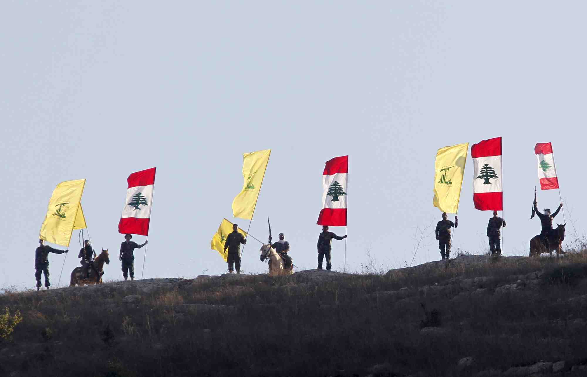 Des membres du hezbollah libanais brandissent des drapeaux du hezbollah et du liban
