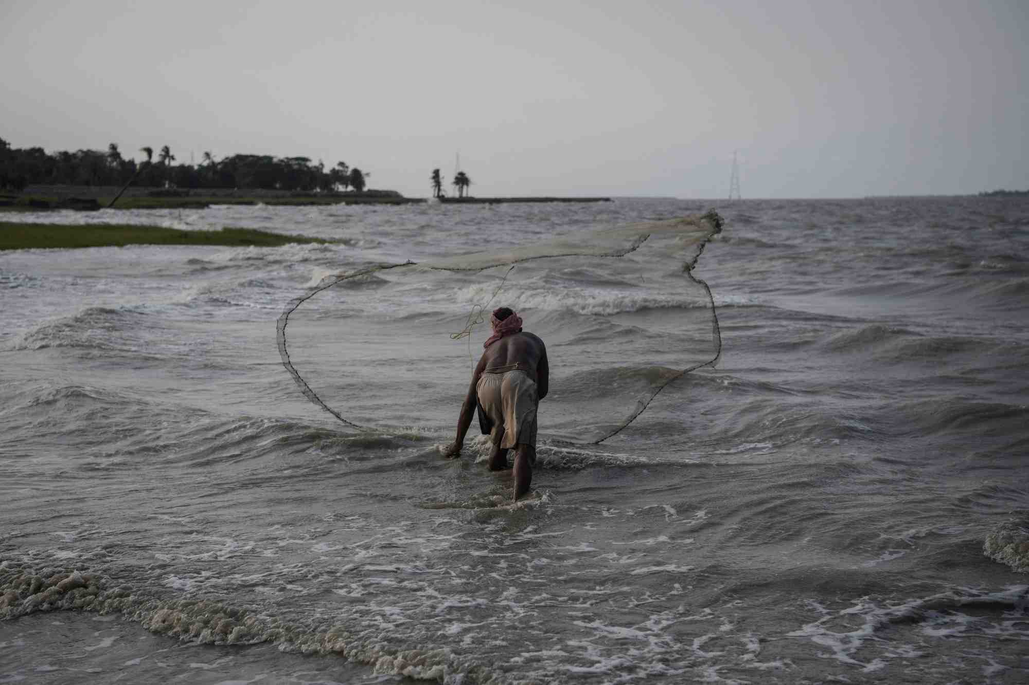 Pratap das, 51 ans, un pecheur, jette un filet de peche dans la riviere hooghly sur l'ile de ghoramara dans les sundarbans, bengale-occidental, inde