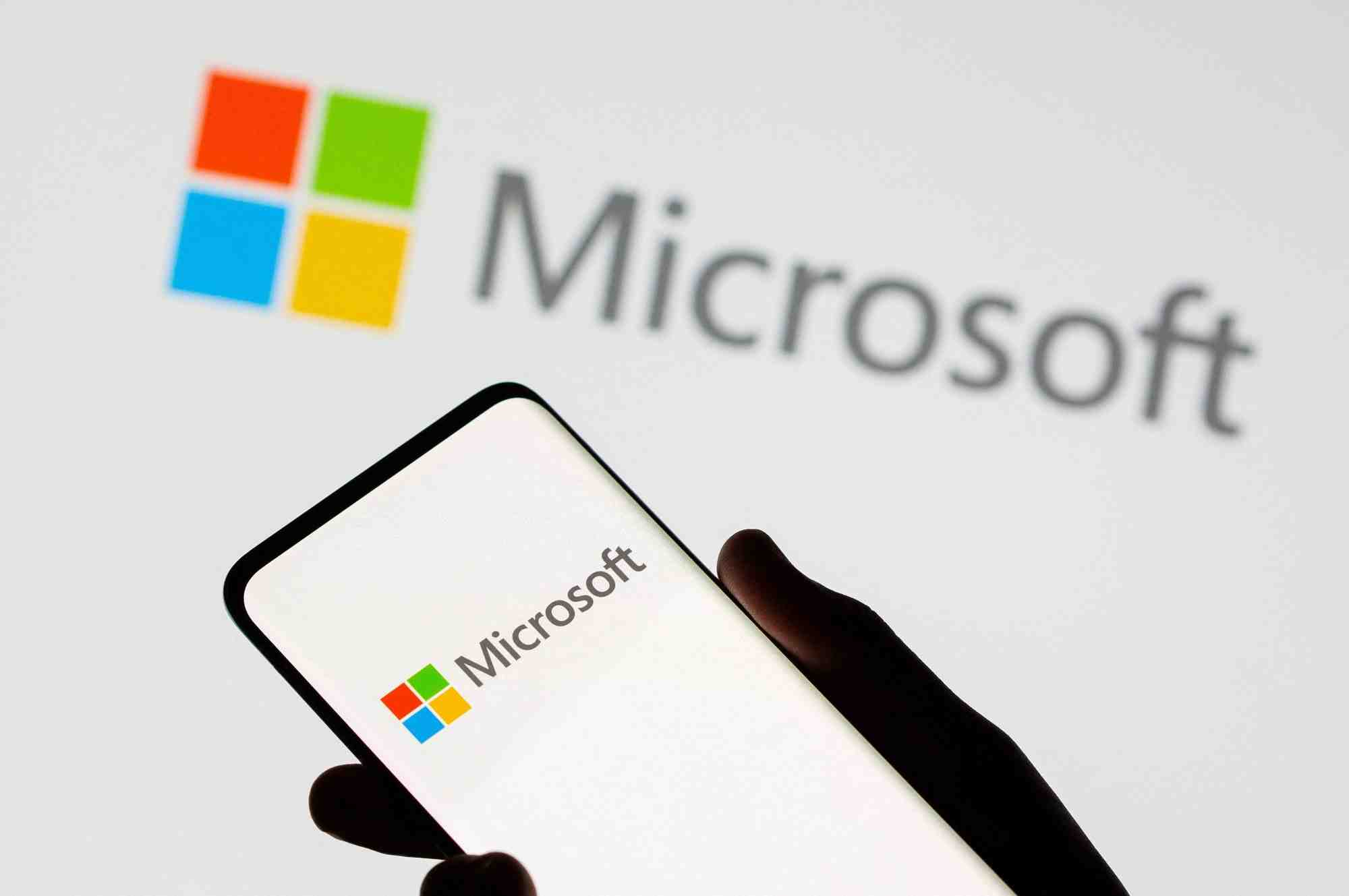 Un smartphone est vu devant le logo de microsoft sur cette illustration