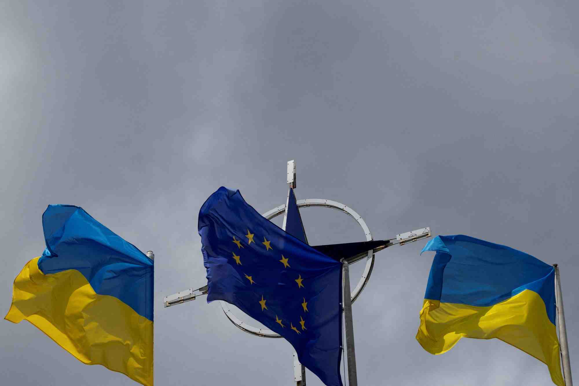 Photo d'archives des drapeaux de l'ukraine et de l'ue qui se dressent devant l'embleme de l'otan au centre de kyiv