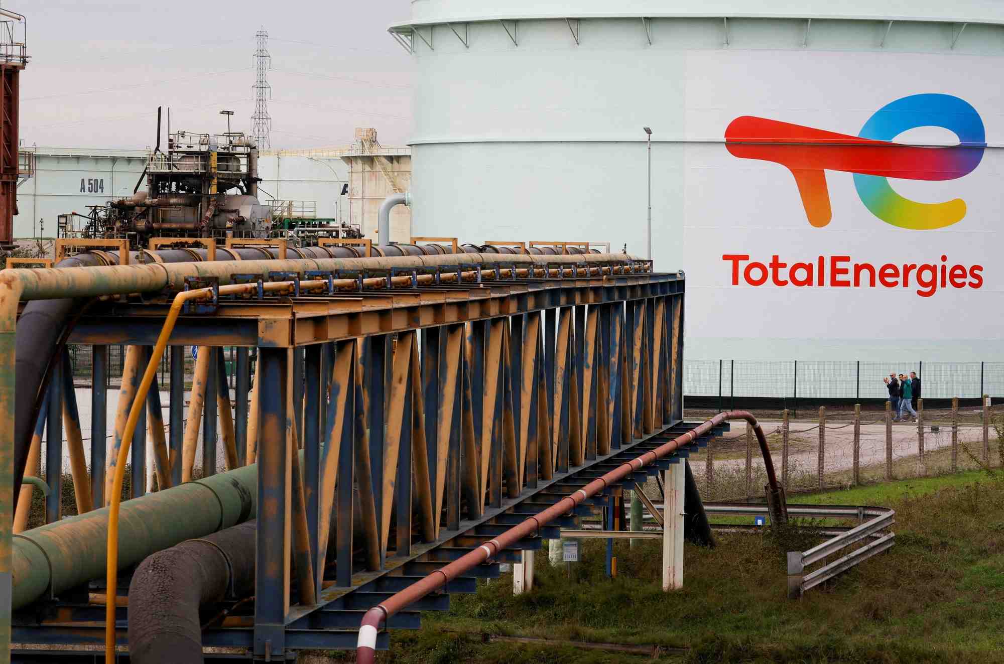 Des travailleurs de totalenergies passent devant un reservoir l'ancienne raffinerie de mardyck