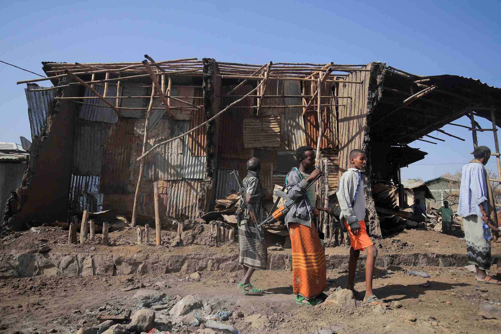 Des habitants et des miliciens a cote de maisons detruites en ethiopie