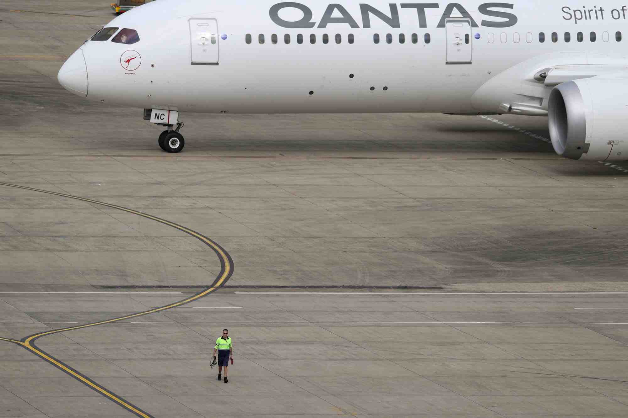 Photo d'archives d'un employe qui marche pres d'un avion qantas a l'aeroport de sydney, en australie