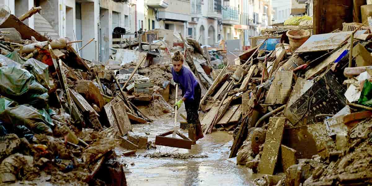 Une femme nettoie la boue parmi les débris dans une rue de Paiporta, au sud de Valence, dans l'est de l'Espagne, le 6 novembre 2024, à la suite d'inondations meurtrières.
