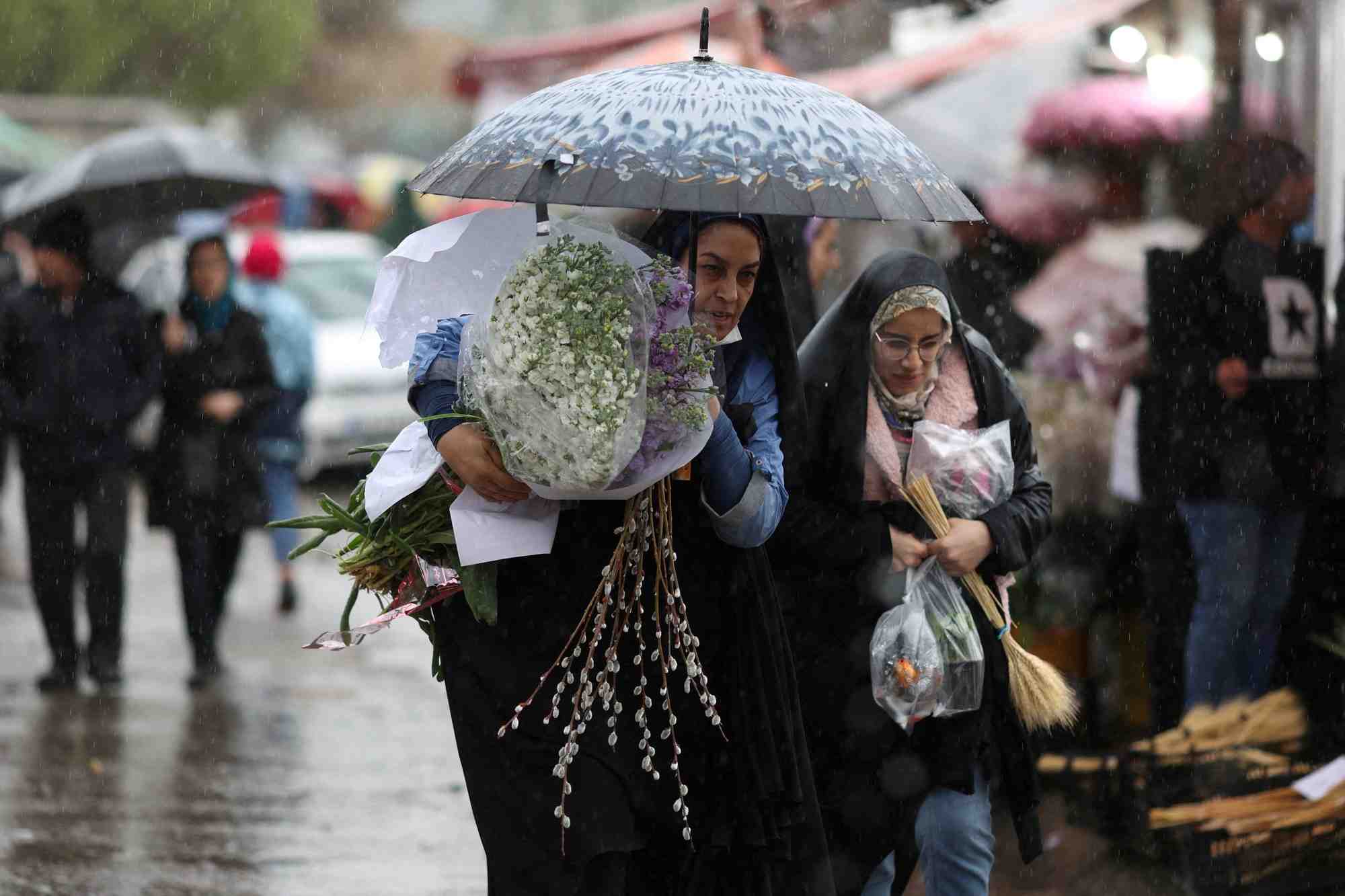 Des femmes iraniennes marchent sous la pluie dans un marche aux fleurs a teheran