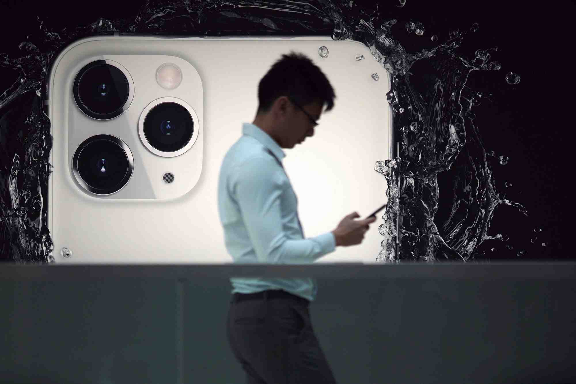 Un homme devant une publicite pour l'iphone 11 pro