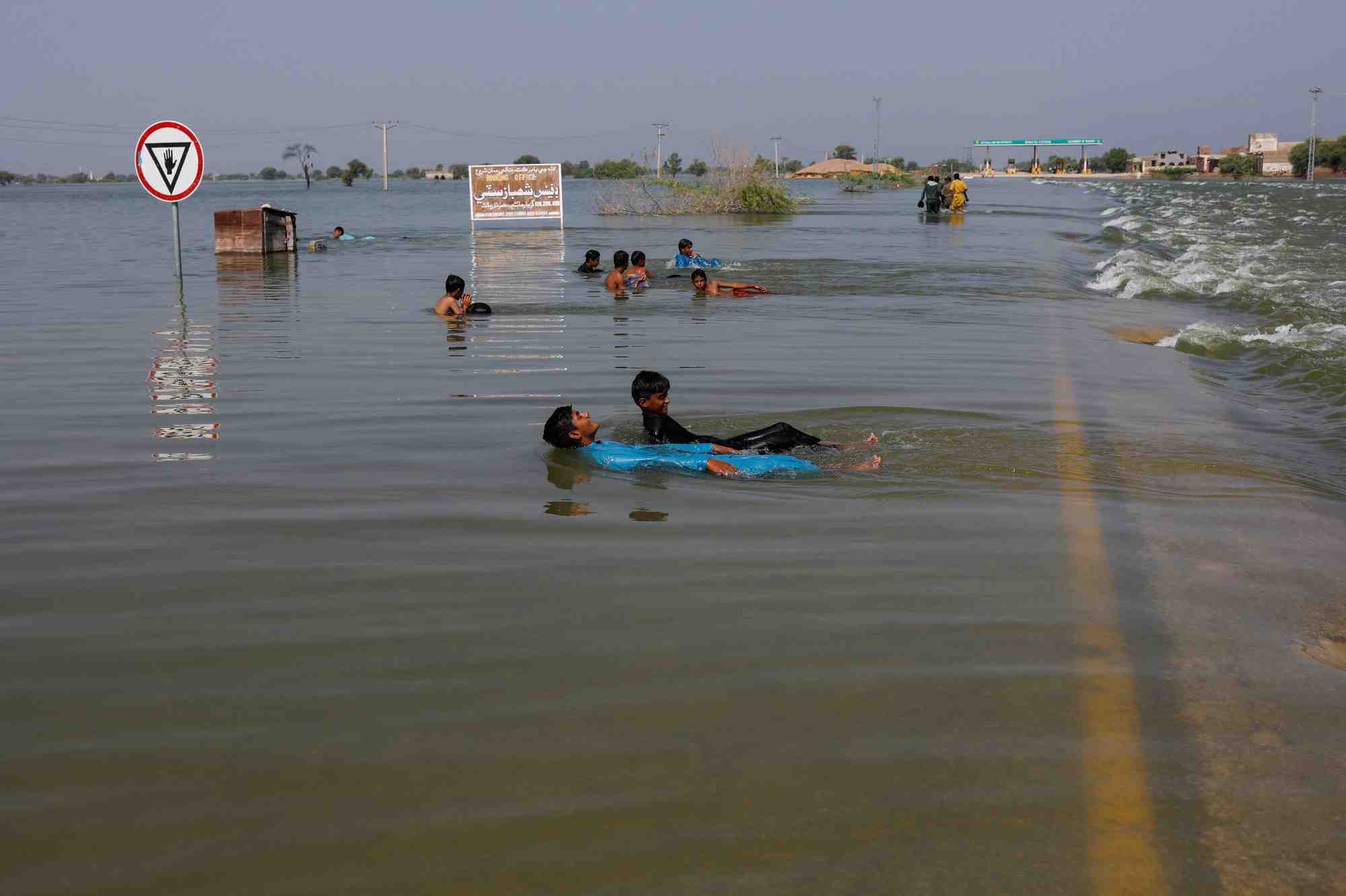 Des garcons jouent dans les eaux de crue sur l'autoroute principale de l'indus, suite aux inondations a sehwan, au pakistan