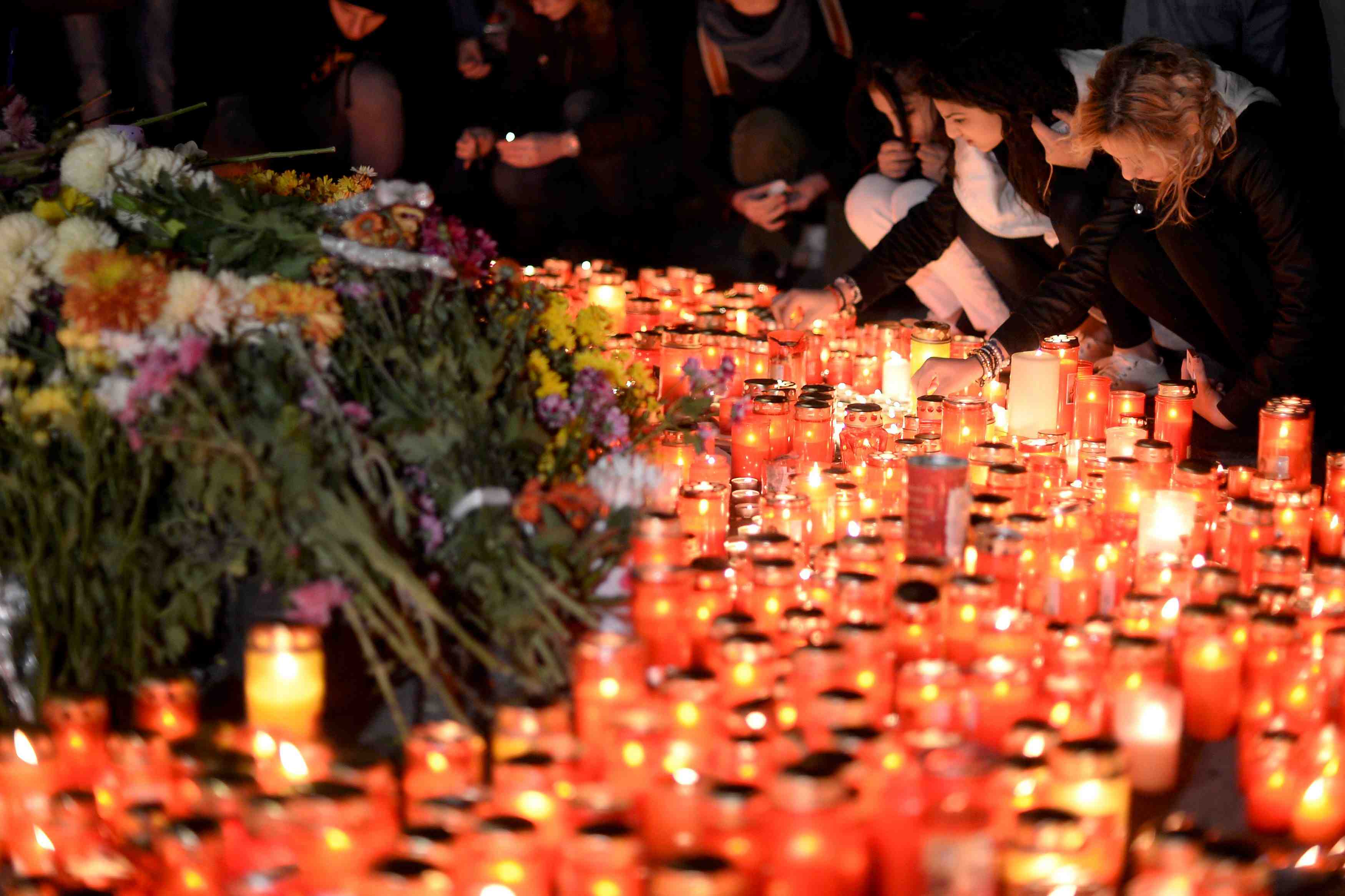 People light candles outside a nightclub, where a fire broke out on friday, in bucharest