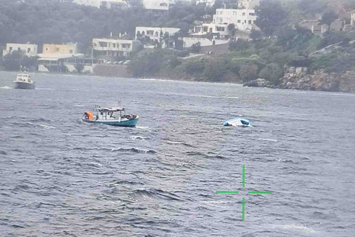 Un bateau de peche s'approche d'un bateau pneumatique a moitie coule qui transportait des migrants au large de l'ile de leros