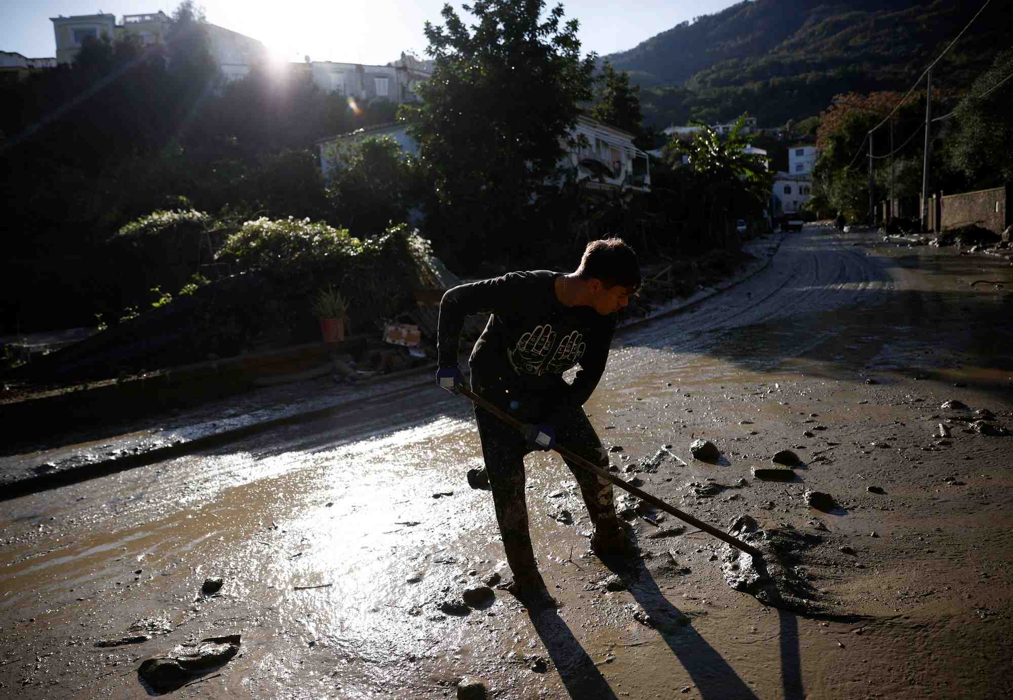 Une personne nettoie une rue couverte de boue, suite a un glissement de terrain sur l'ile italienne d'ischia
