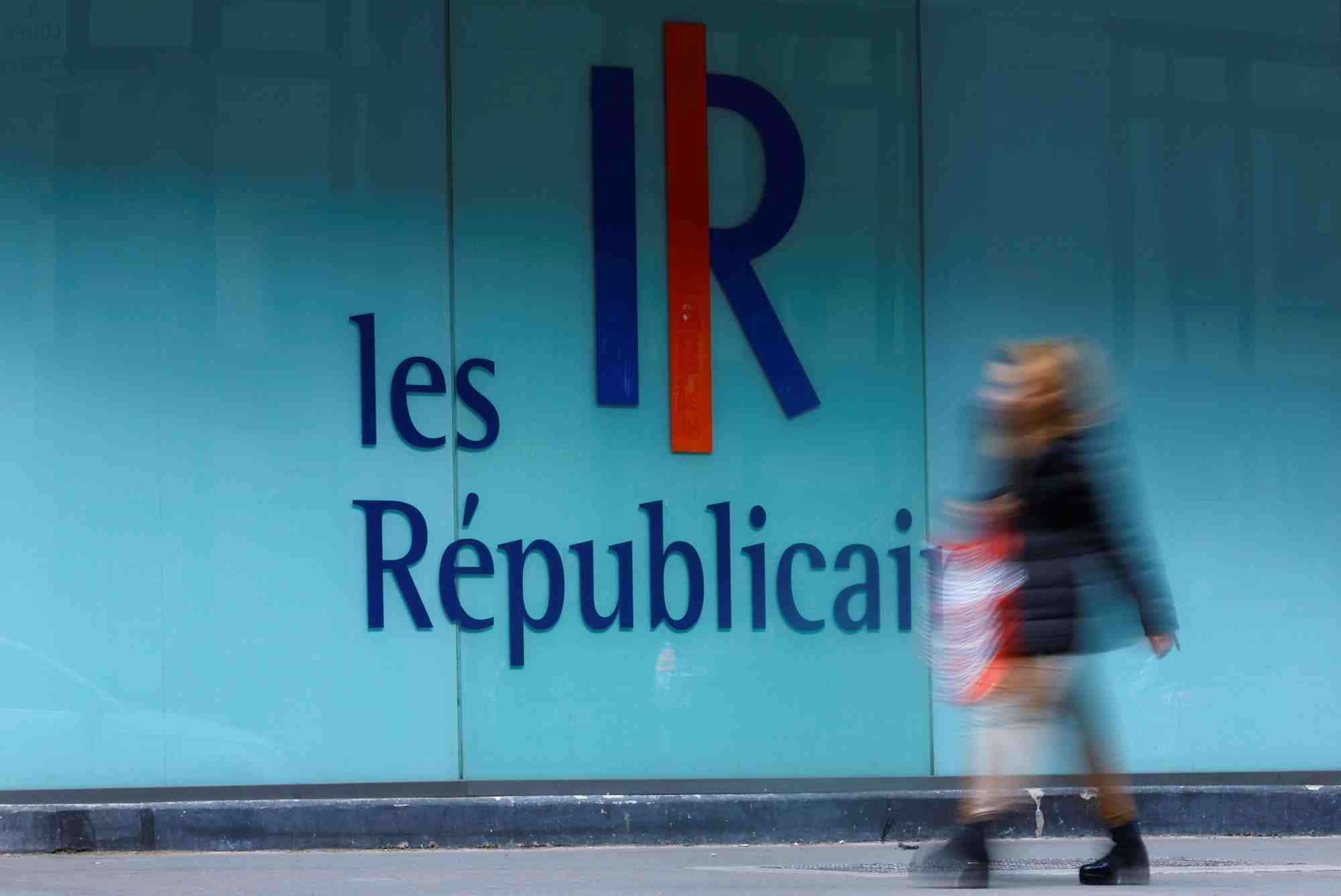 Une femme passe devant un logo du parti francais les republicains (lr) a paris, france