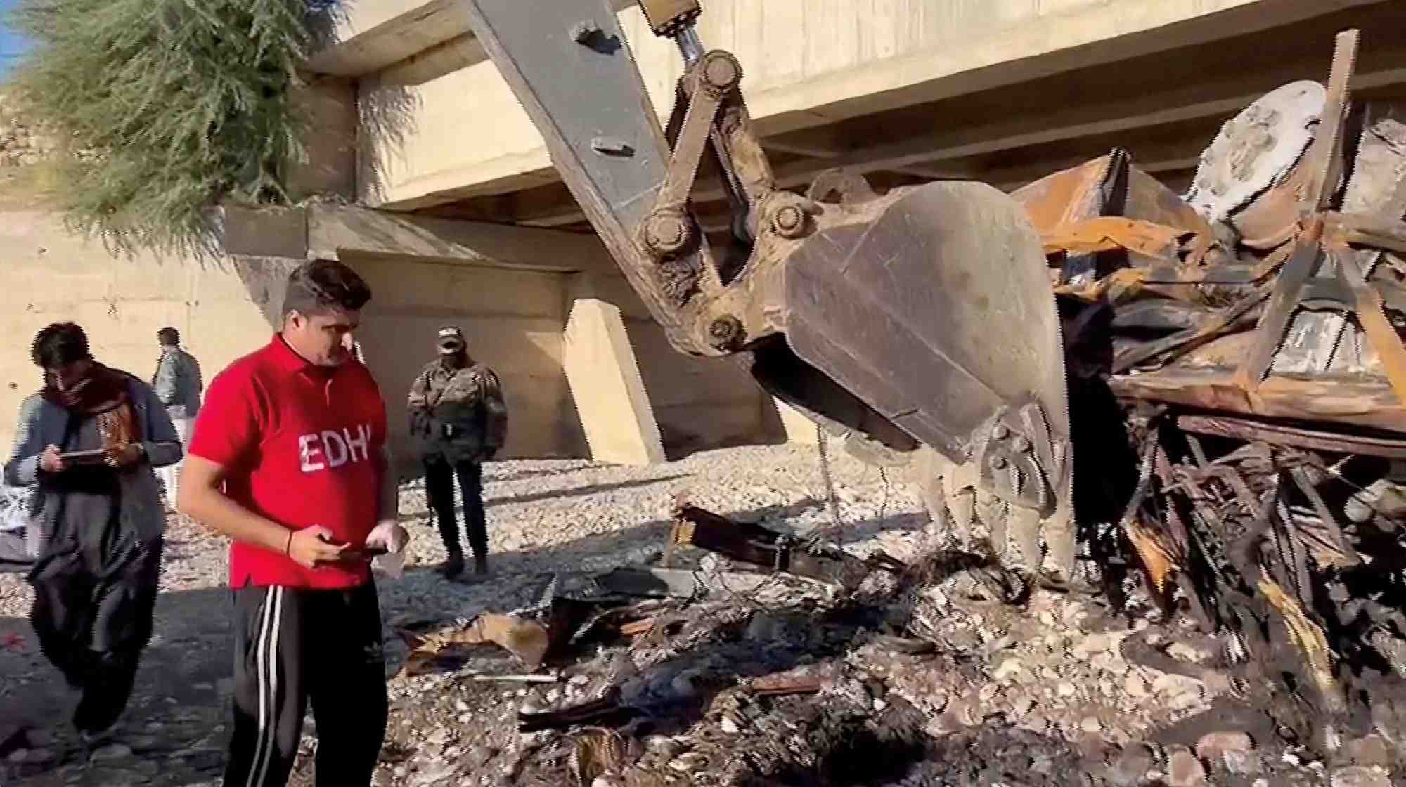 Des personnes travaillent sur le site d'un accident de bus dans le district de lasbela