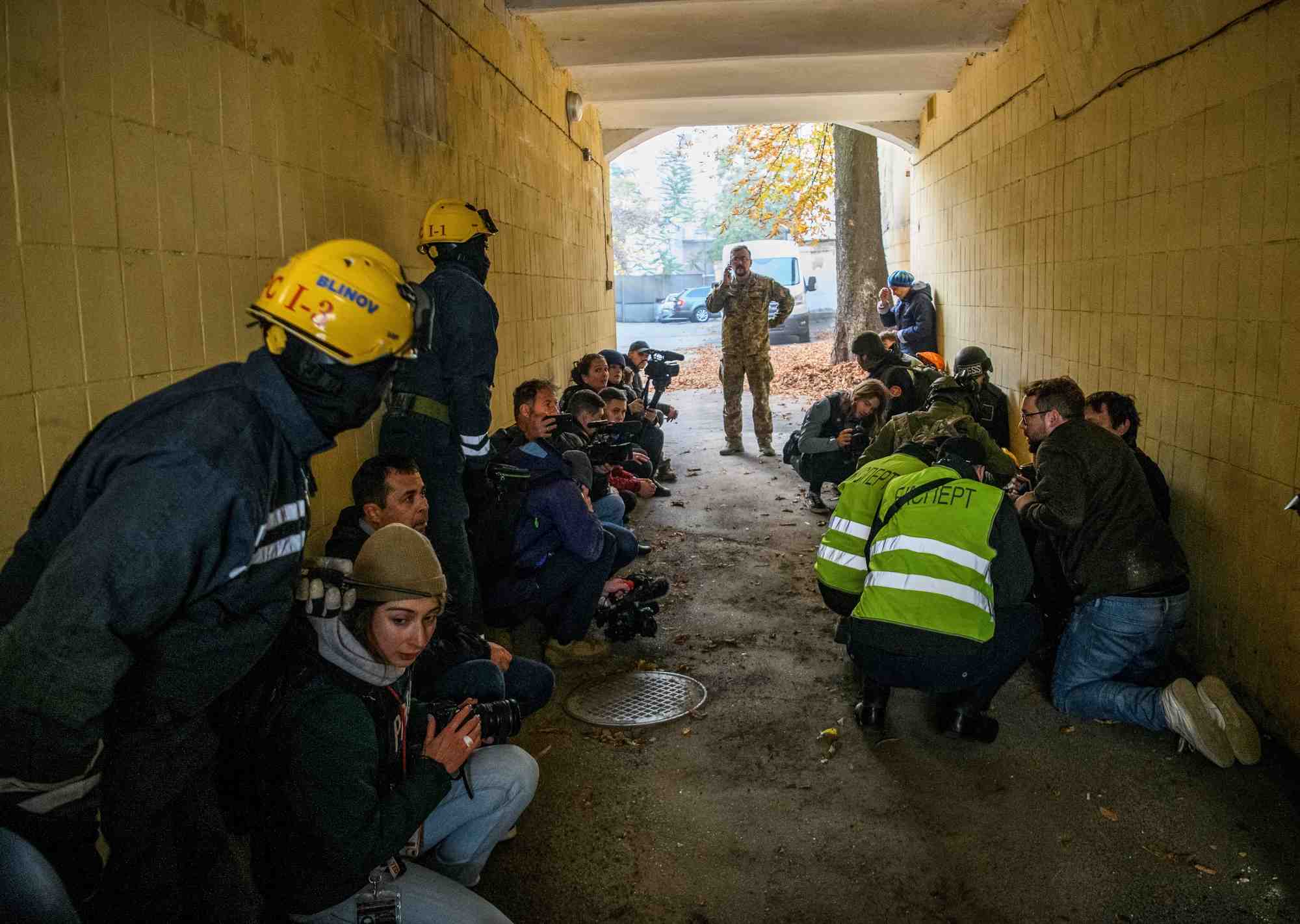 Des personnes secourues, des journalistes et des policiers se mettent a l'abri alors qu'une sirene d'alerte aerienne retentit lors d'une frappe de drone russe a kiev, ukraine