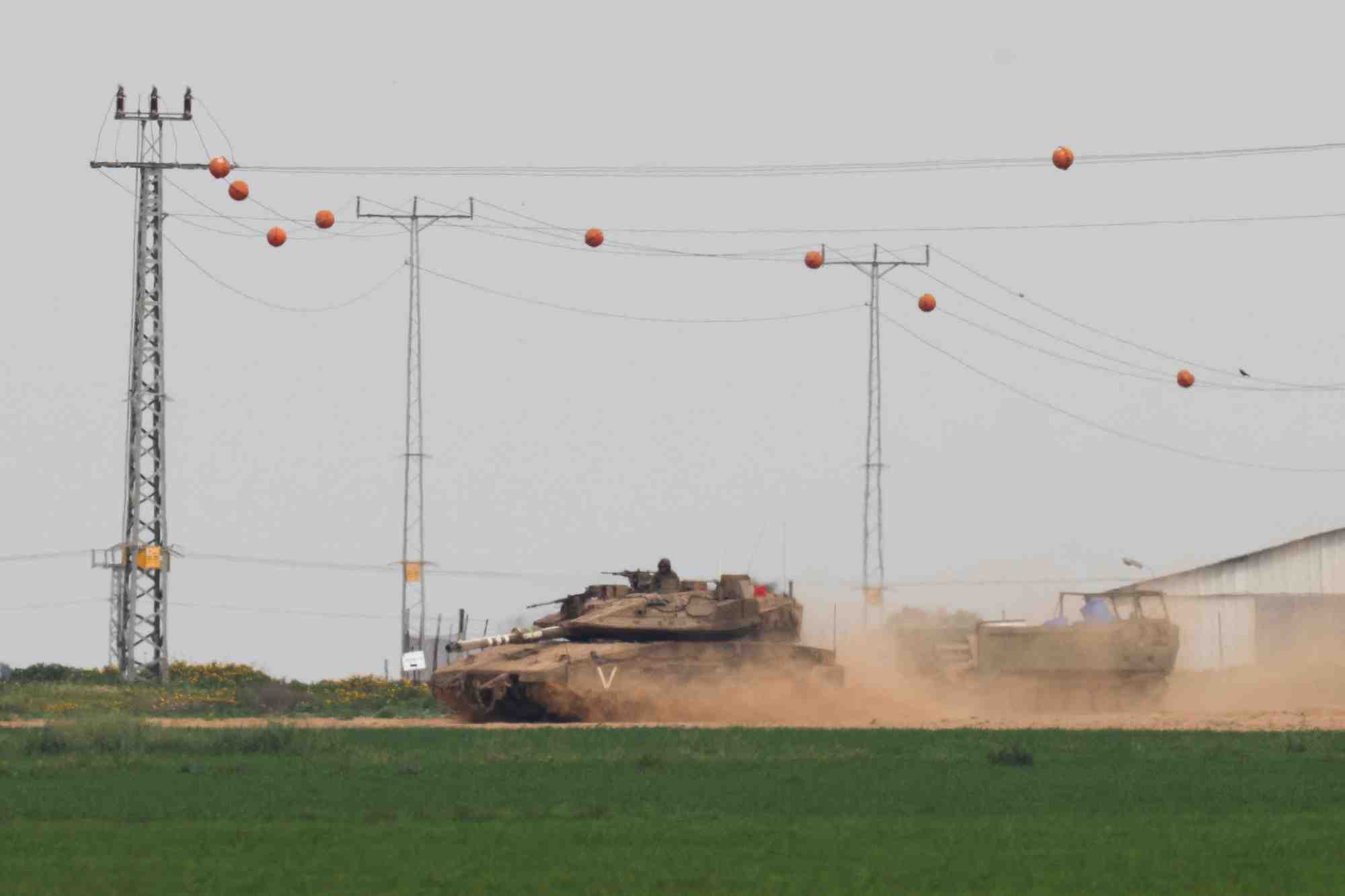 Photo d'un un char israelien qui tire un vehicule blinde de transport de troupes (apc) pres de la frontiere entre israel et gaza