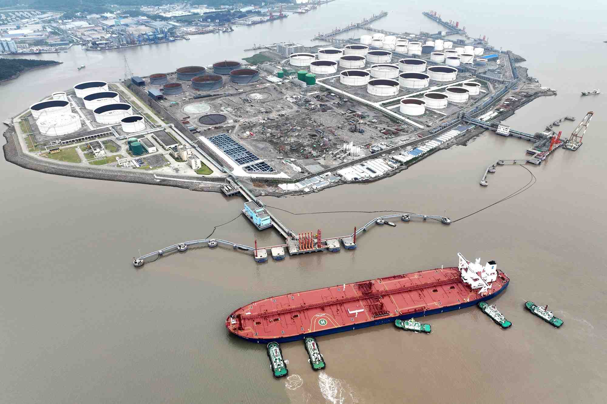 Des remorqueurs aident un petrolier a s'amarrer a un terminal petrolier, au large de l'ile de waidiao a zhoushan