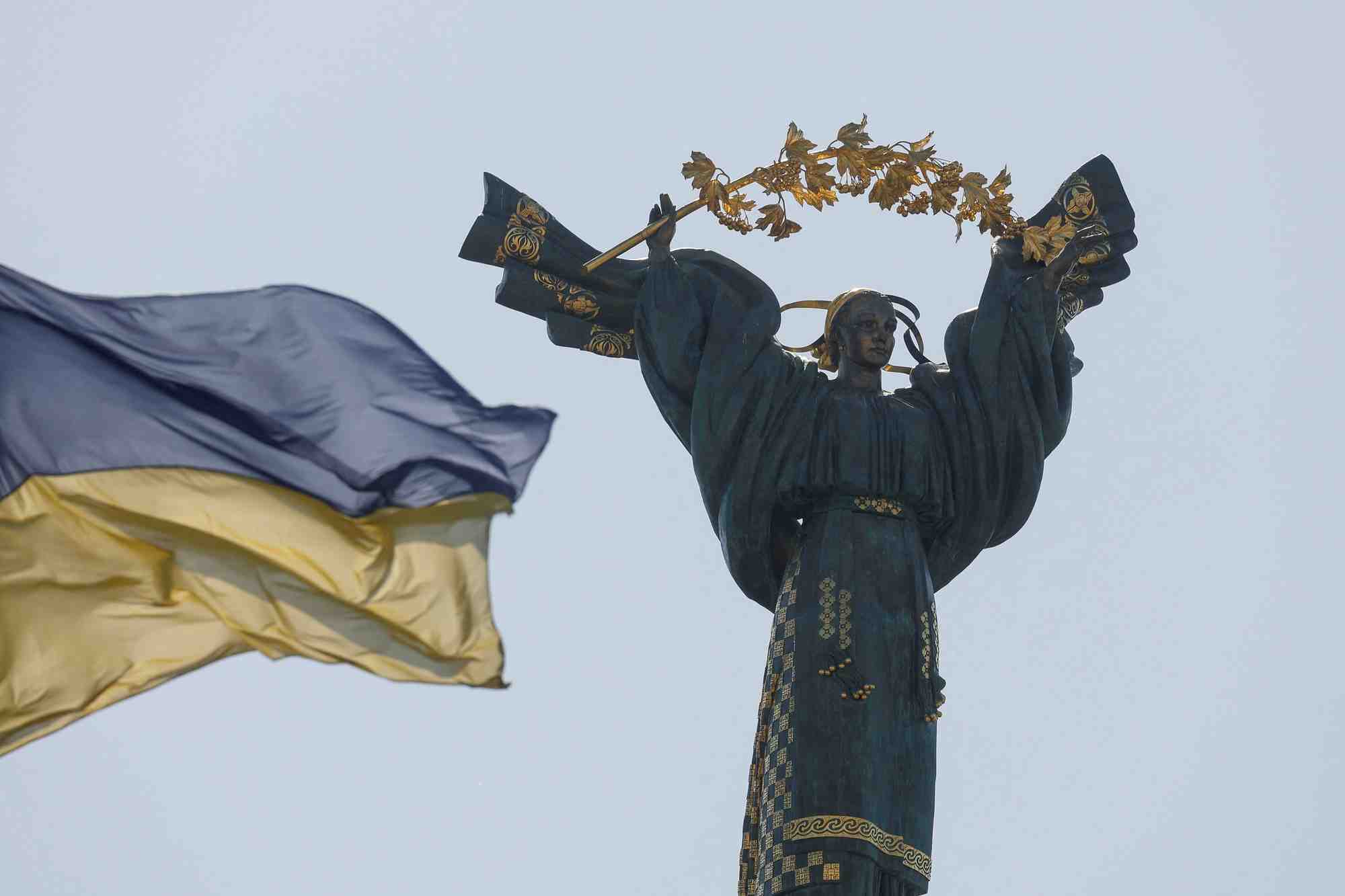 Un drapeau national ukrainien flotte devant le monument de l'independance dans le centre de kyiv