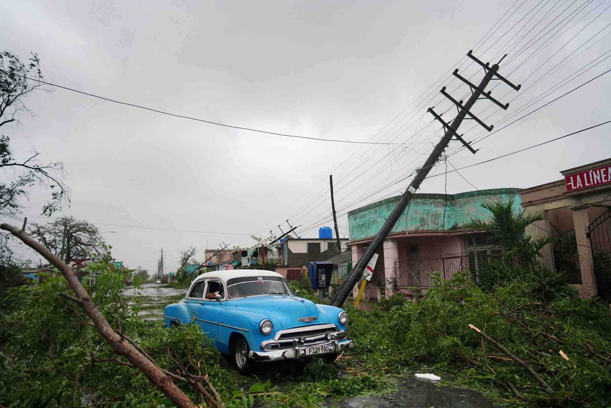 Une voiture de collection passe a cote de debris causes par l'ouragan ian lors de son passage a pinar del rio, a cuba