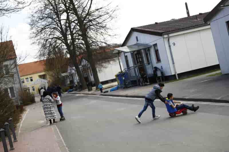 Children play outside at camp for migrants and refugees in friedland