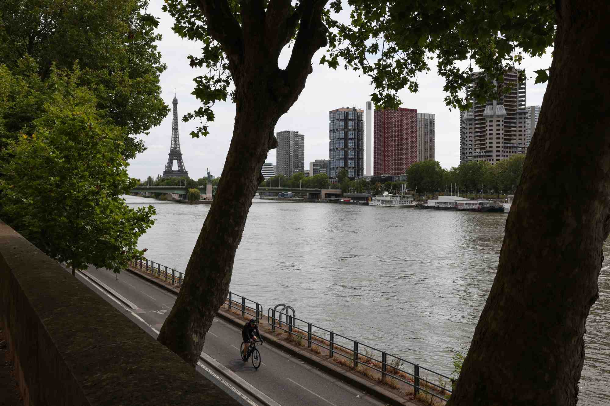 Un homme roule a velo sur les rives de la seine avec la tour eiffel en arriere-plan