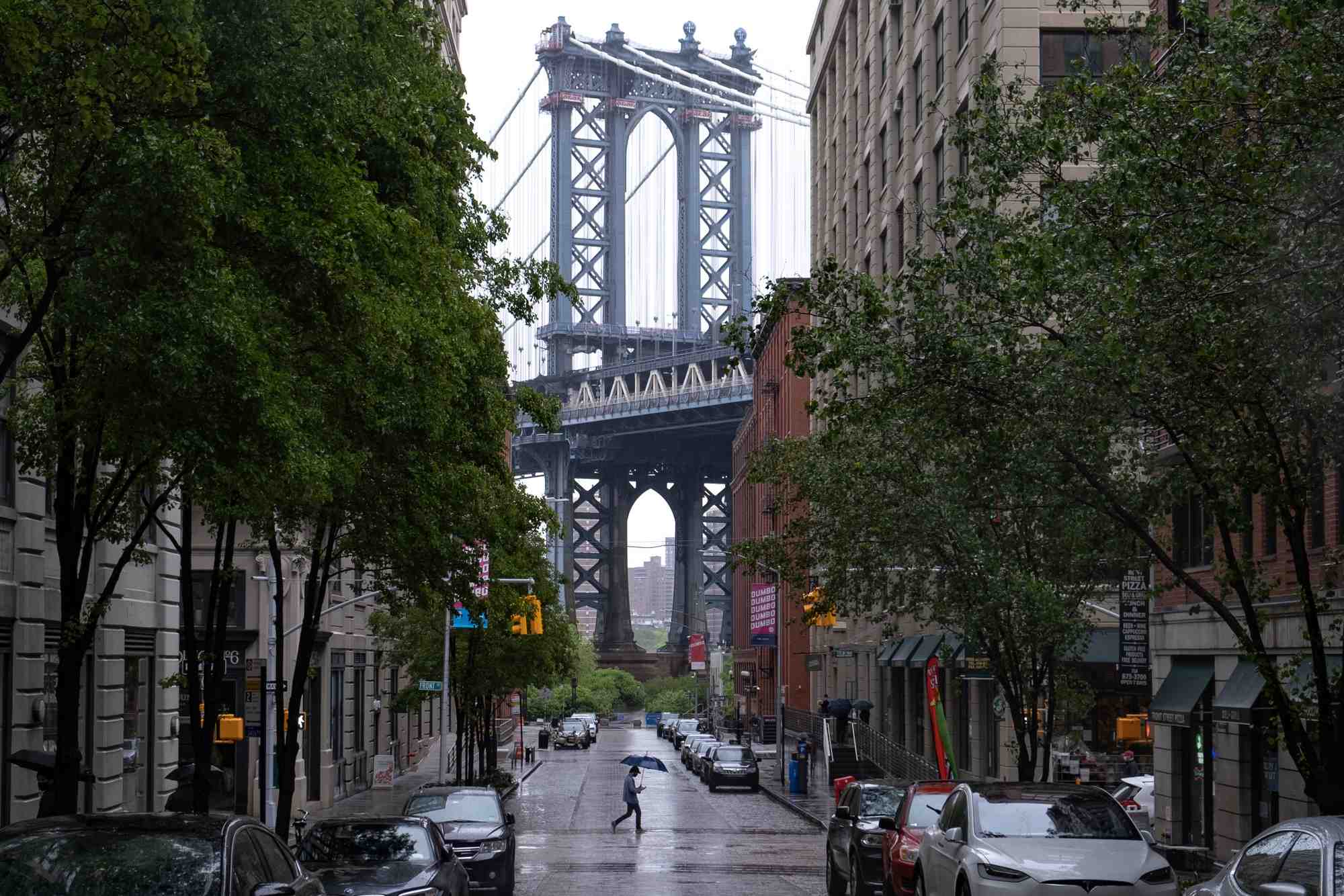 Un pieton passe sur washington street dans le quartier de dumbo a brooklyn, avec le pont de manhattan en arriere-plan, a new york