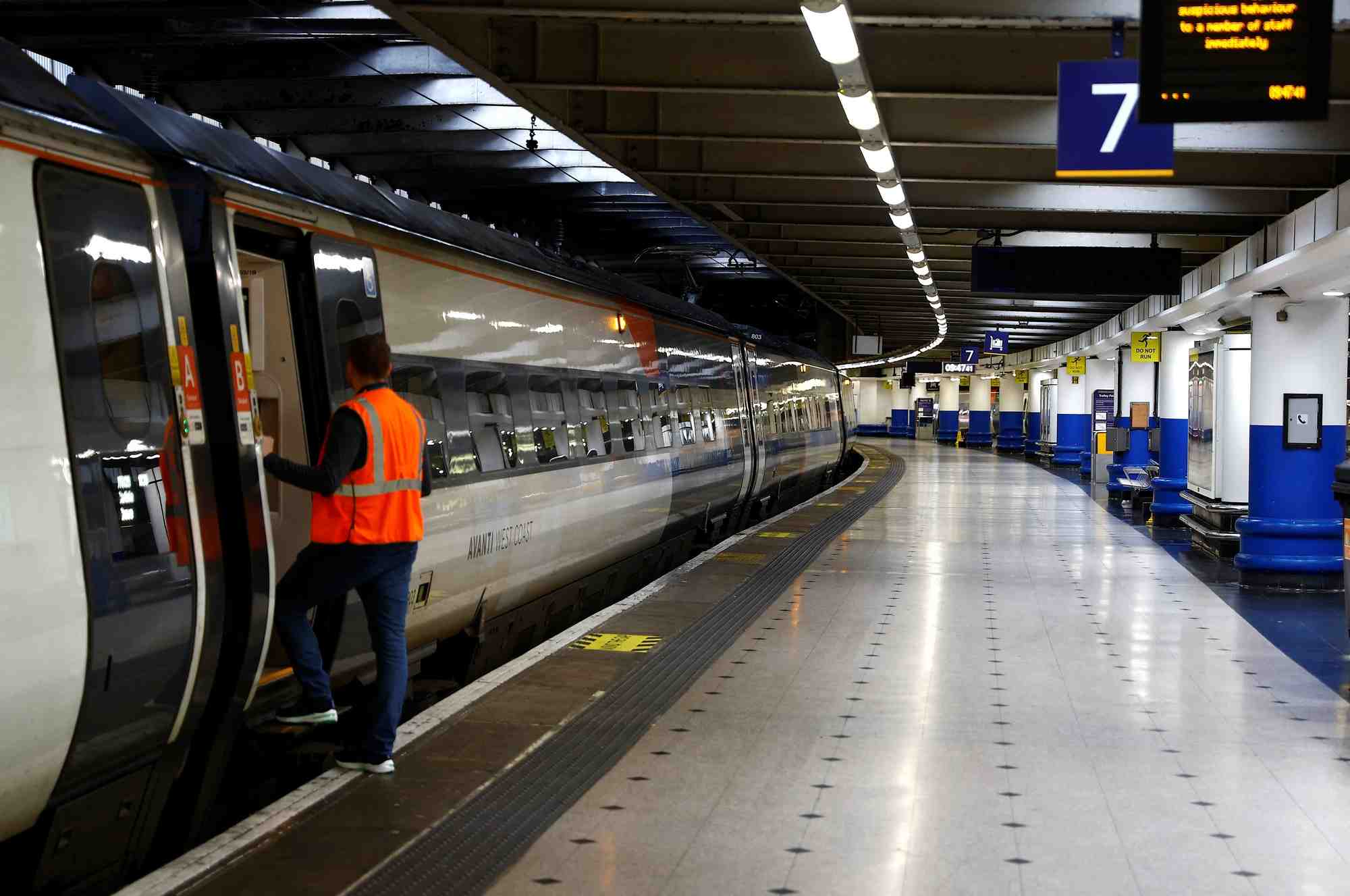 Un employe ferroviaire a cote d'un train a la gare d'euston a londres, en grande-bretagne