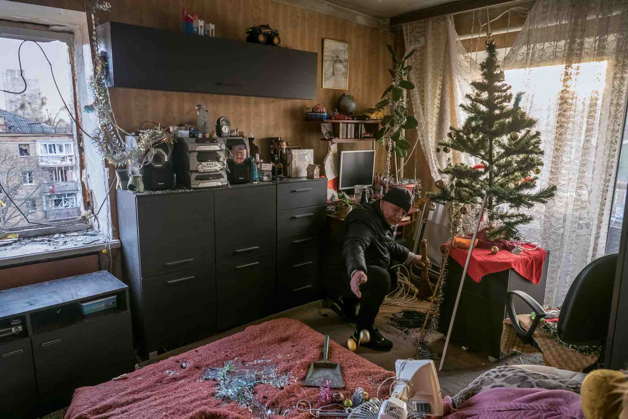 Un habitant enleve les morceaux de verre des fenetres brisees de son appartement, dans un immeuble residentiel endommage par un tir de missile russe, a kyiv
