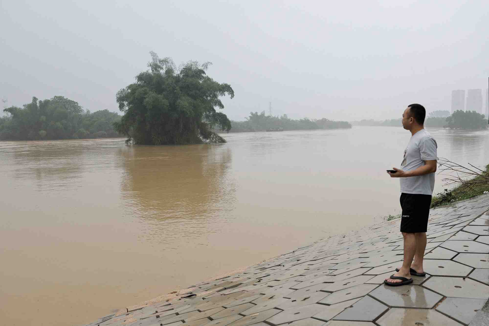 Photo d'un habitant pres d'une riviere en crue suite a de fortes pluies a qingyuan