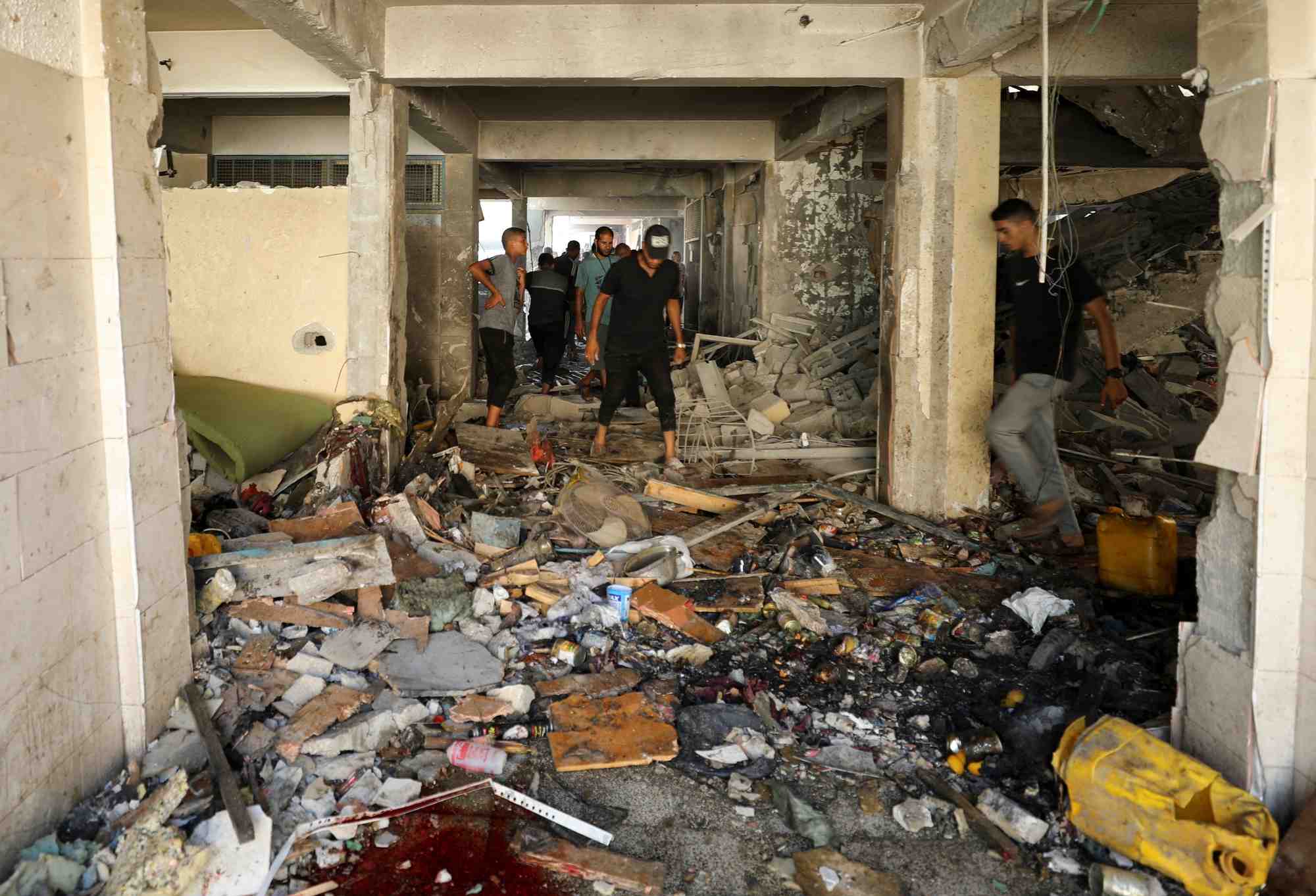 Palestinians inspect a school after it was hit by an israeli strike, in gaza city