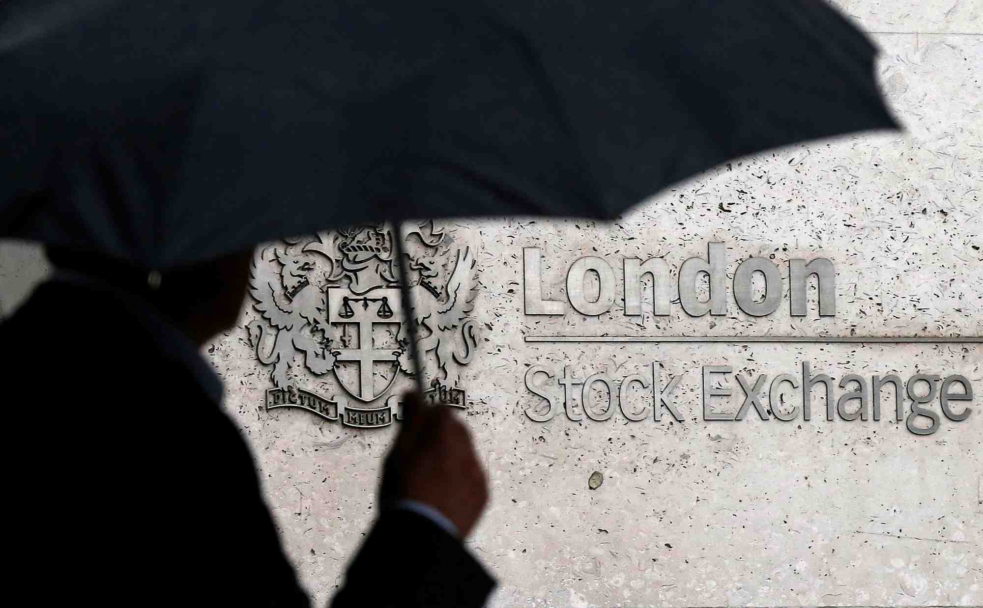 Un homme s'abrite sous un parapluie alors qu'il passe devant la bourse de londres