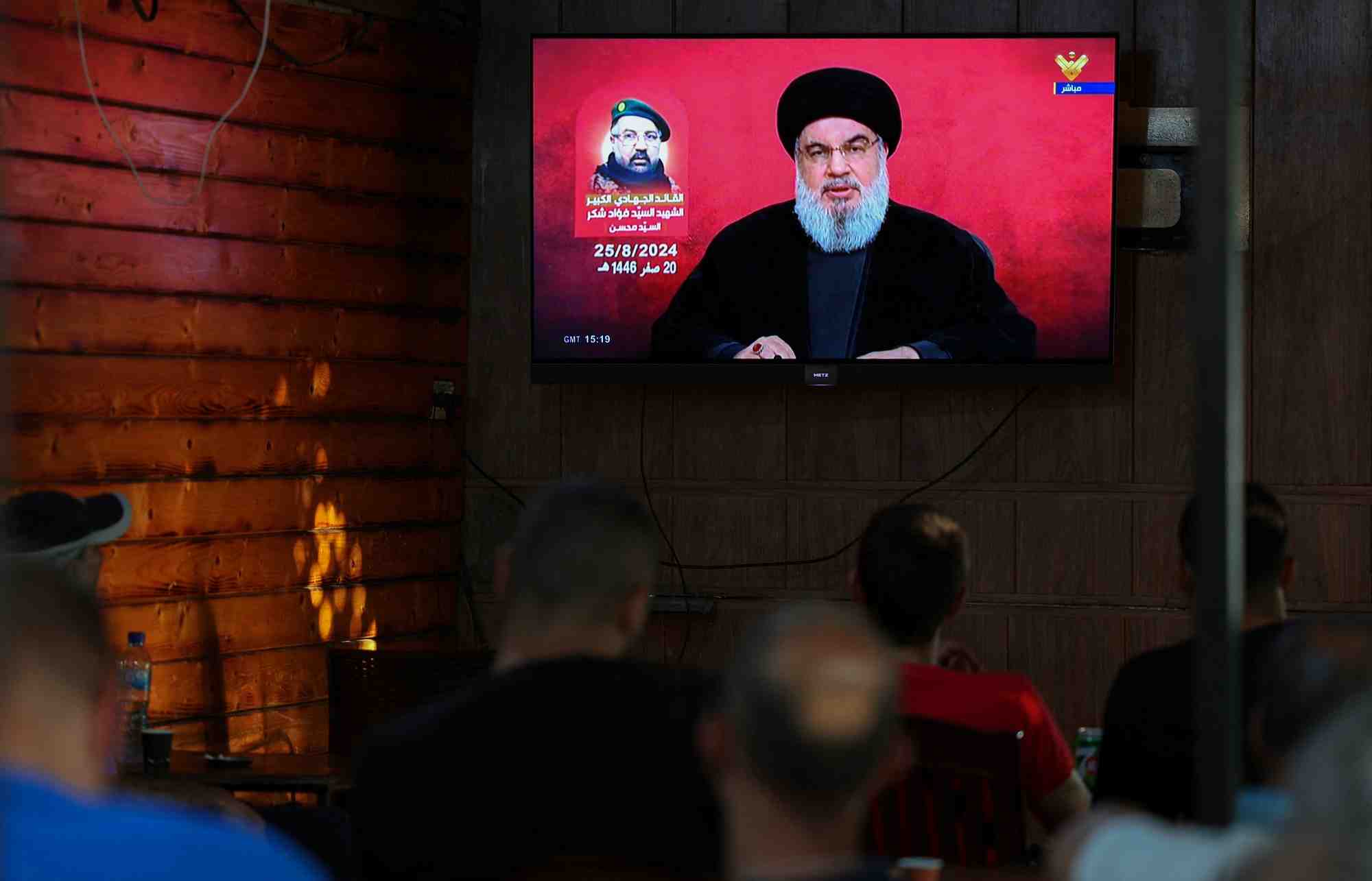 Des personnes regardent le chef du hezbollah libanais, sayyed hassan nasrallah, prononcer un discours televise