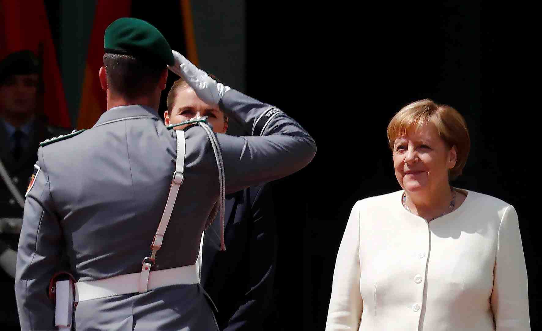 Angela merkel assise lors d'une ceremonie d'honneurs militaires
