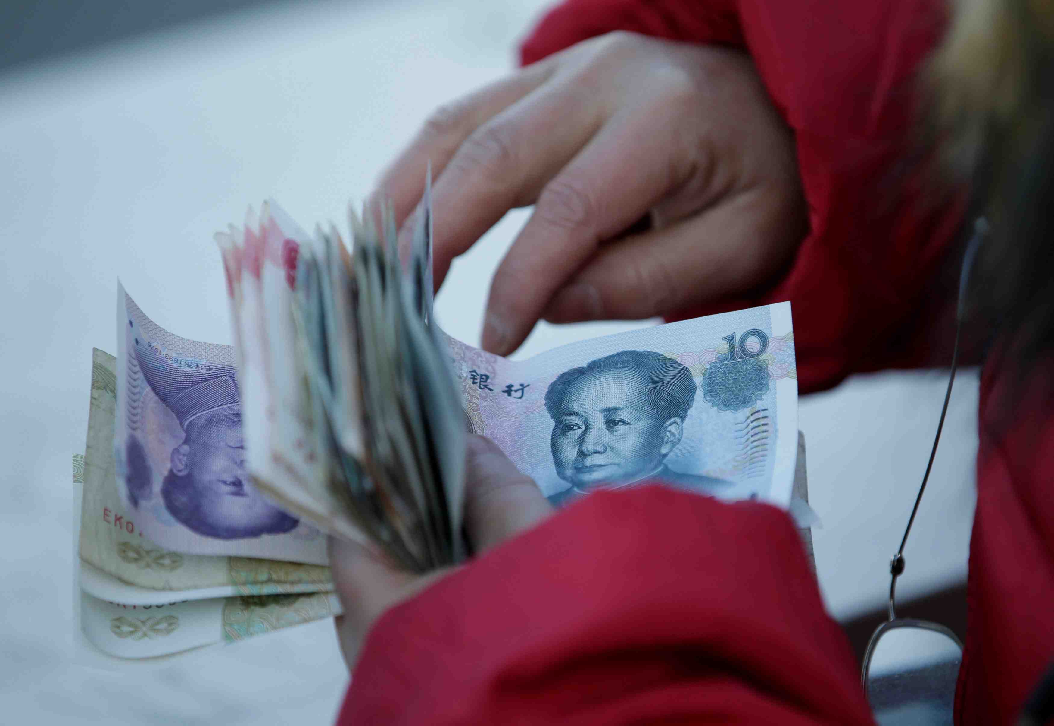 A woman counts chinese yuan banknotes as she sells tickets for a job fair in beijing